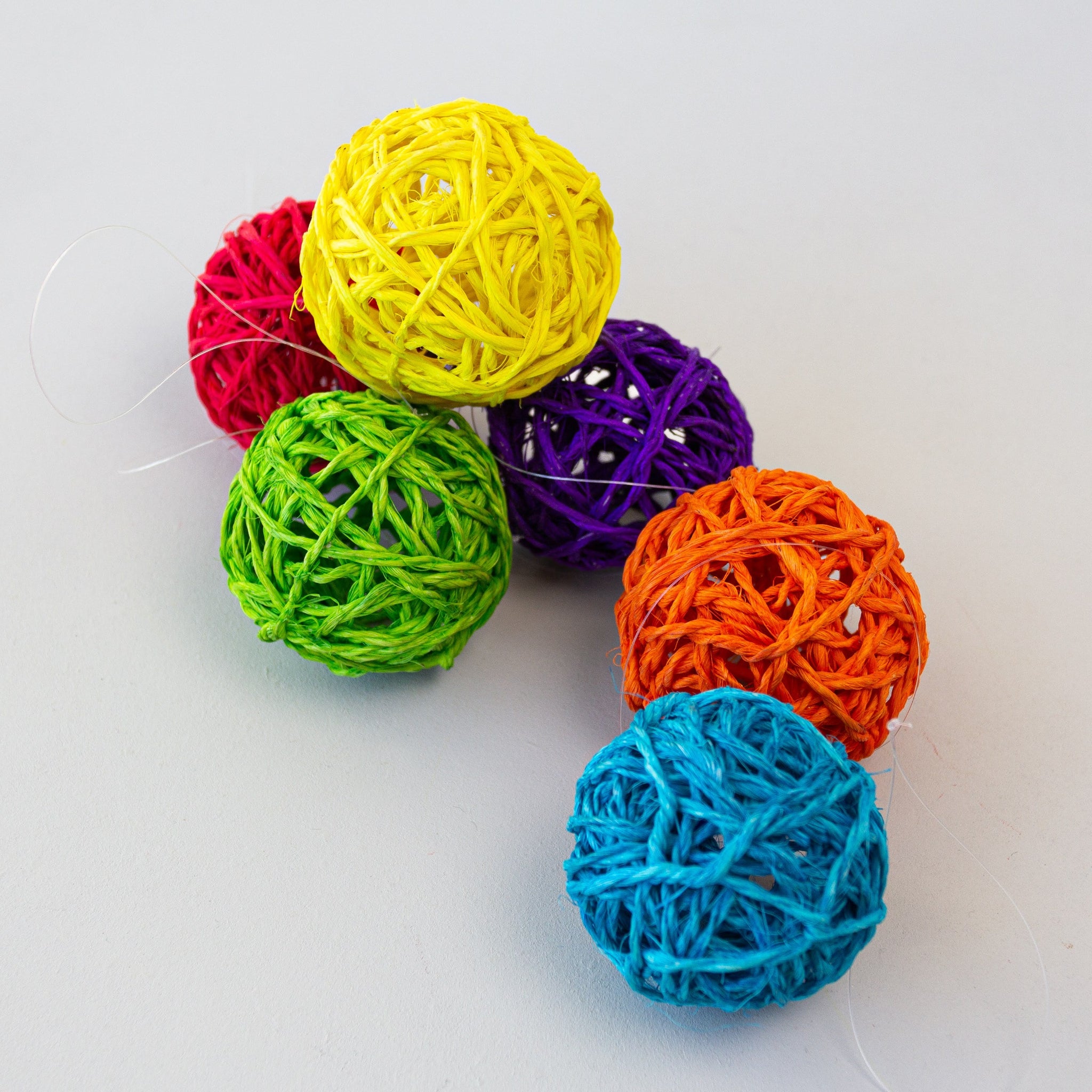 A set of six multicolored sisal ball ornaments in red, yellow, purple, orange, green, and blue, displayed against a white background.
