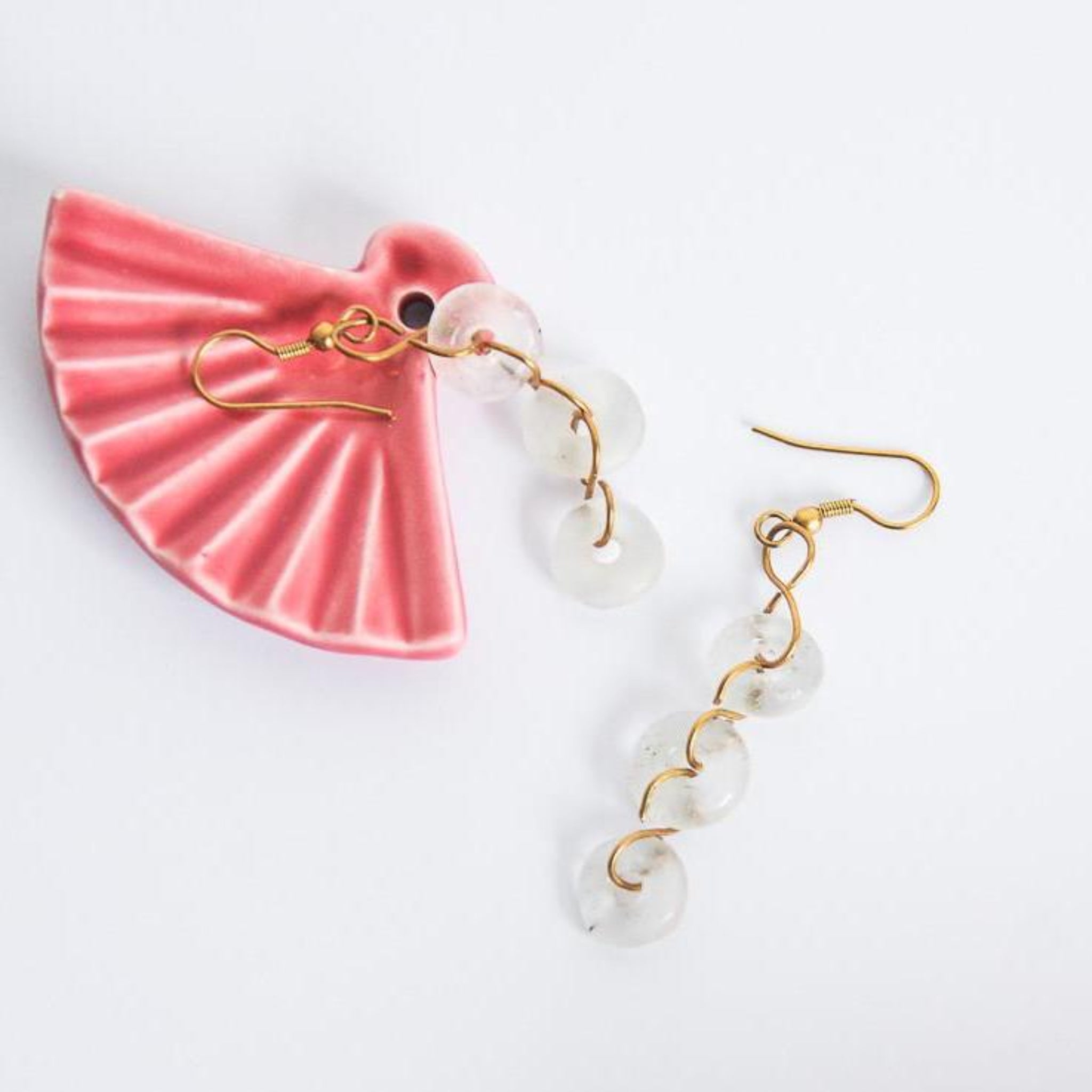 A pair of dangle earrings made with white glass beads and gold-colored metal, displayed against a light background.