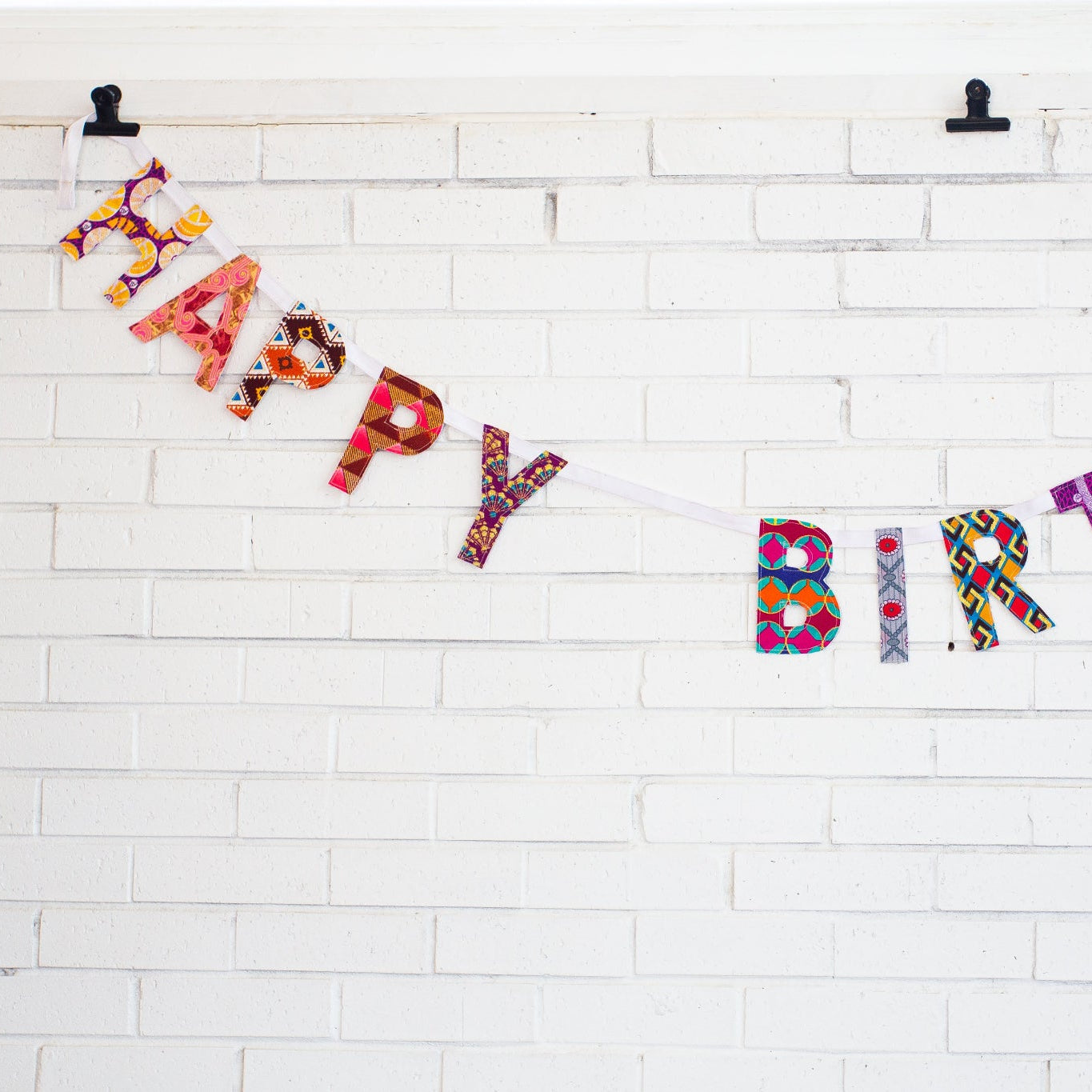 Colorful 'Happy Birthday' banner on a white brick wall