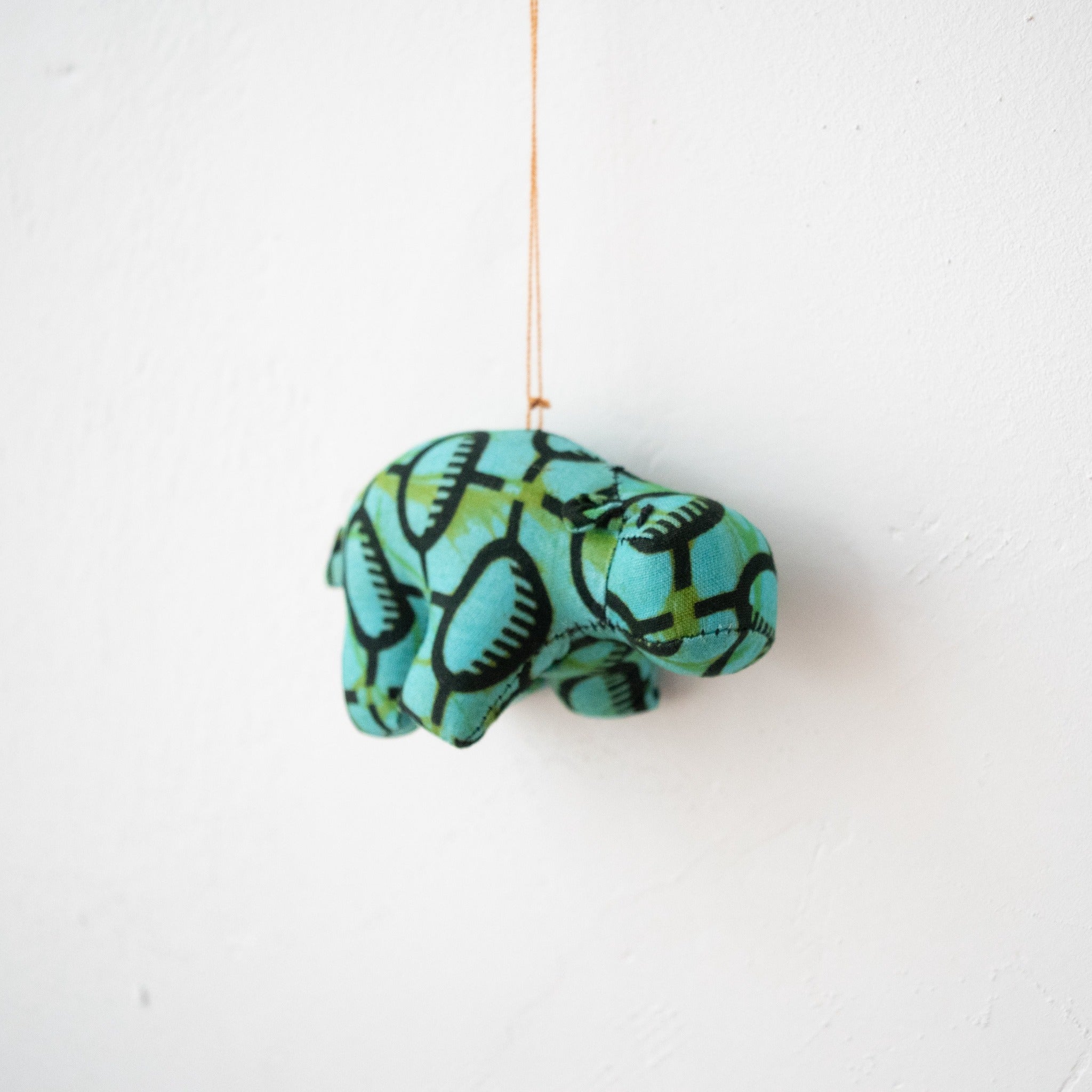 Stuffed hippo ornament hanging on white background
