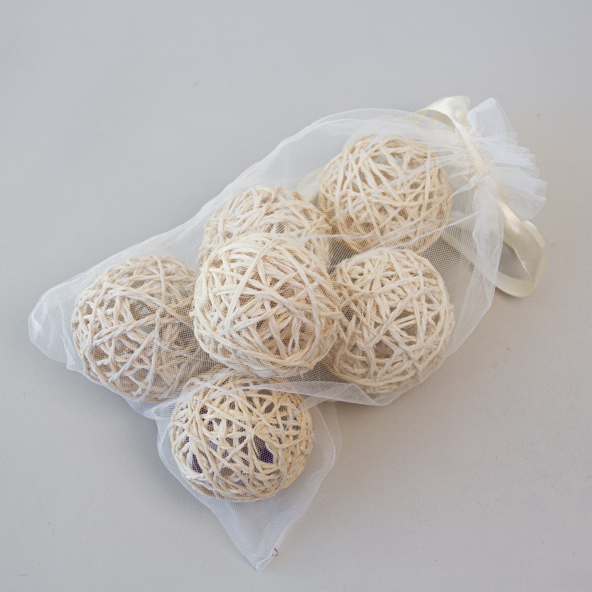 Set of beige sisal balls in a sheer white bag on a light gray background