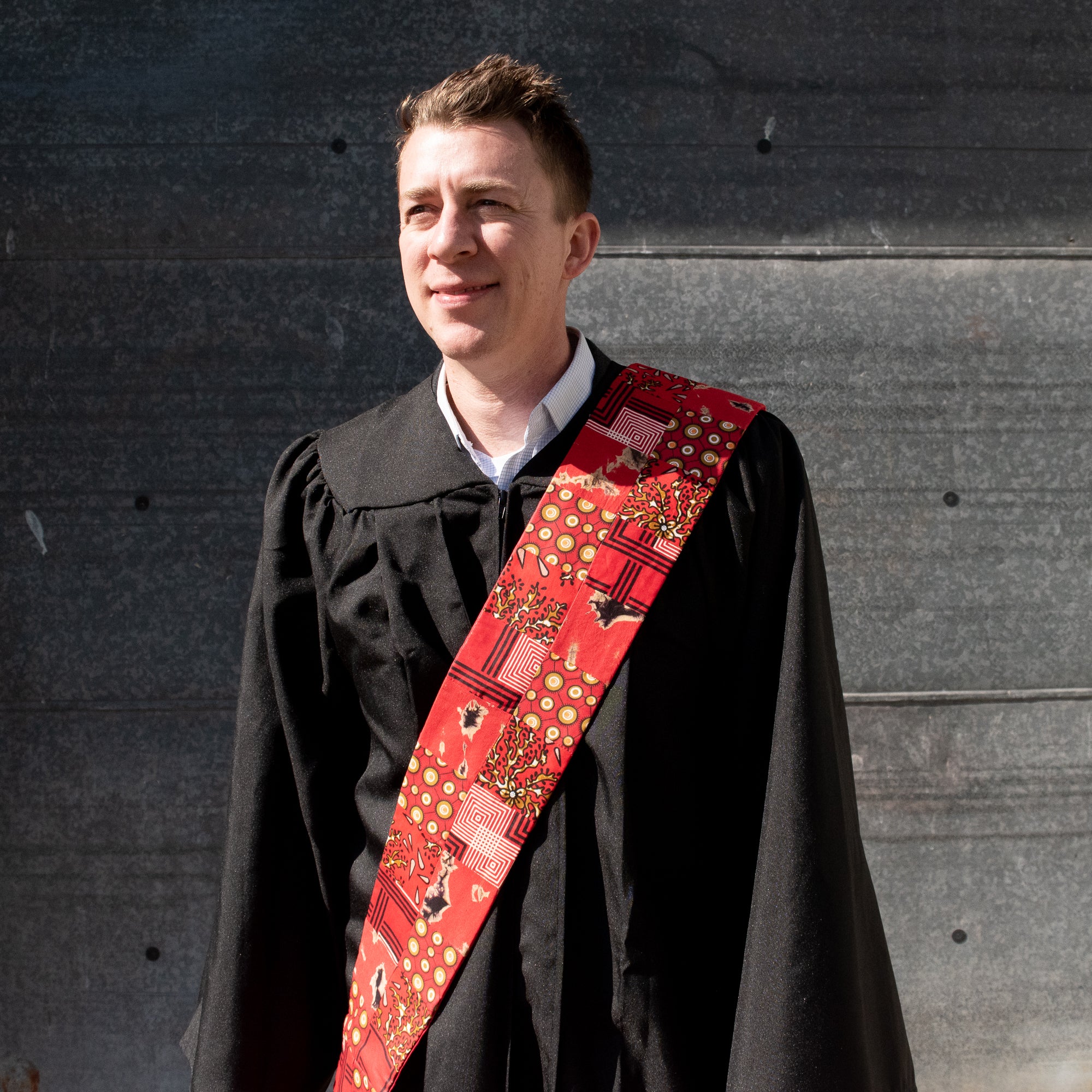 Man in black robe wearing red patch deacon stole