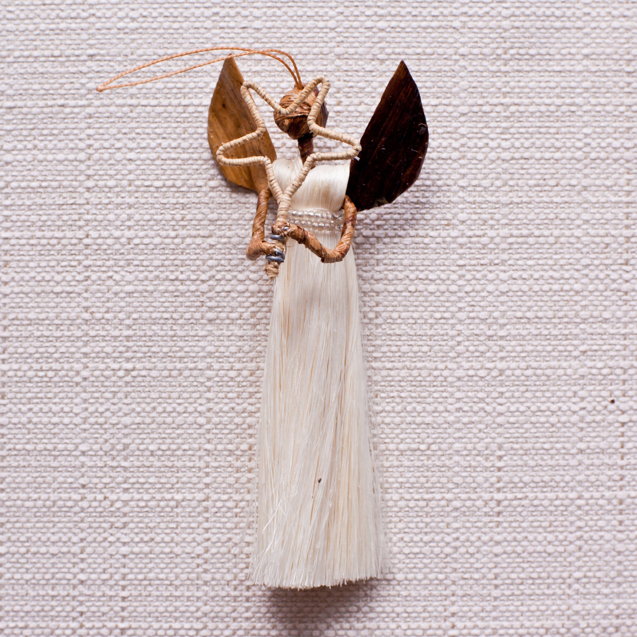 Sisal angel ornament holding star on a white background