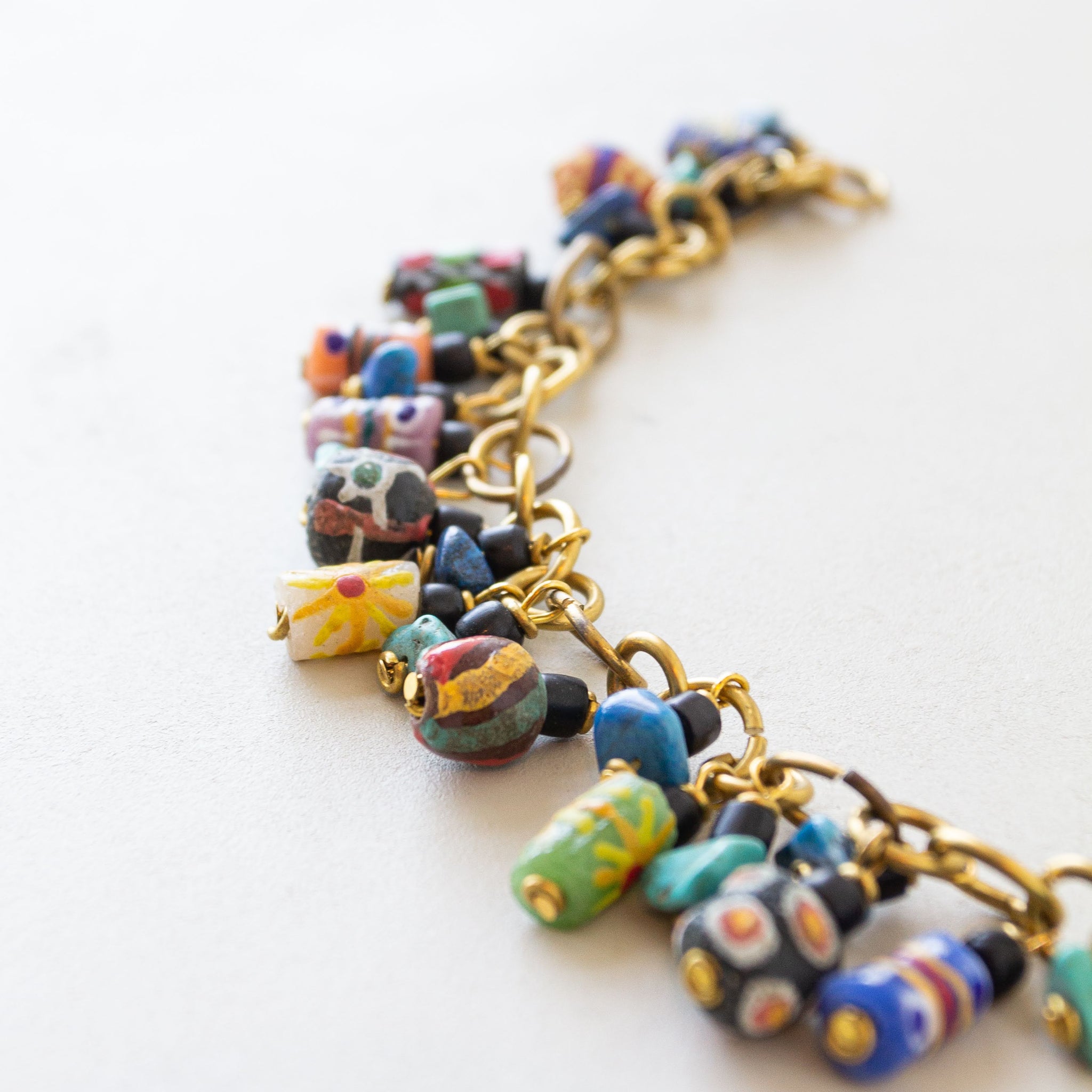 Colorful beaded bracelet with gold chain on a white background