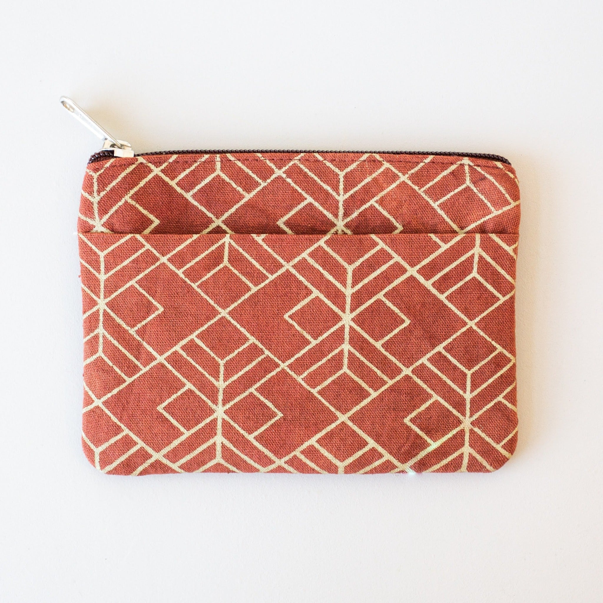 A rust coin purse with a geometric pattern, displayed on a white surface.