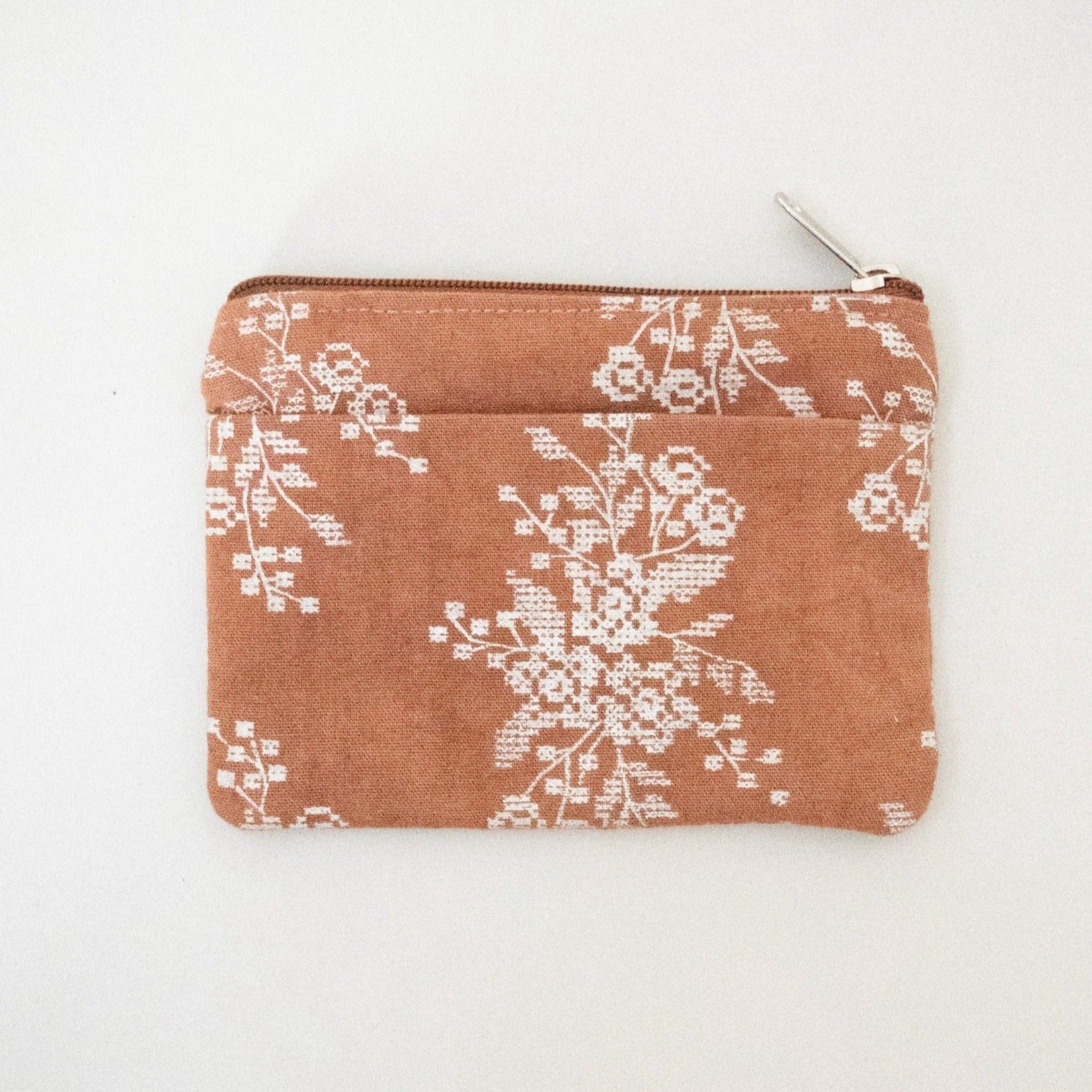Copper colored coin purse with a floral pattern on a white background.