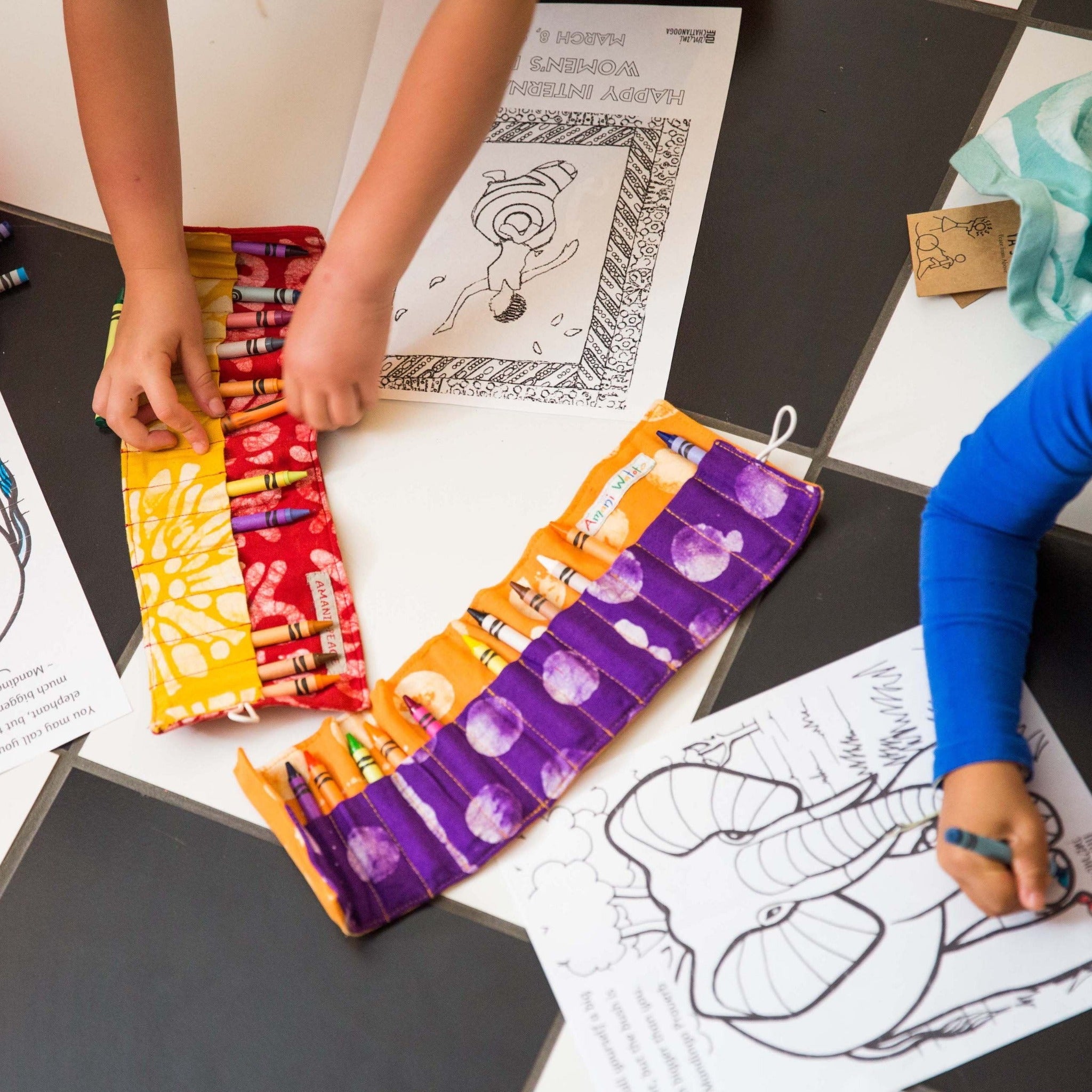 Children coloring on pages and using fabric crayon pouches.