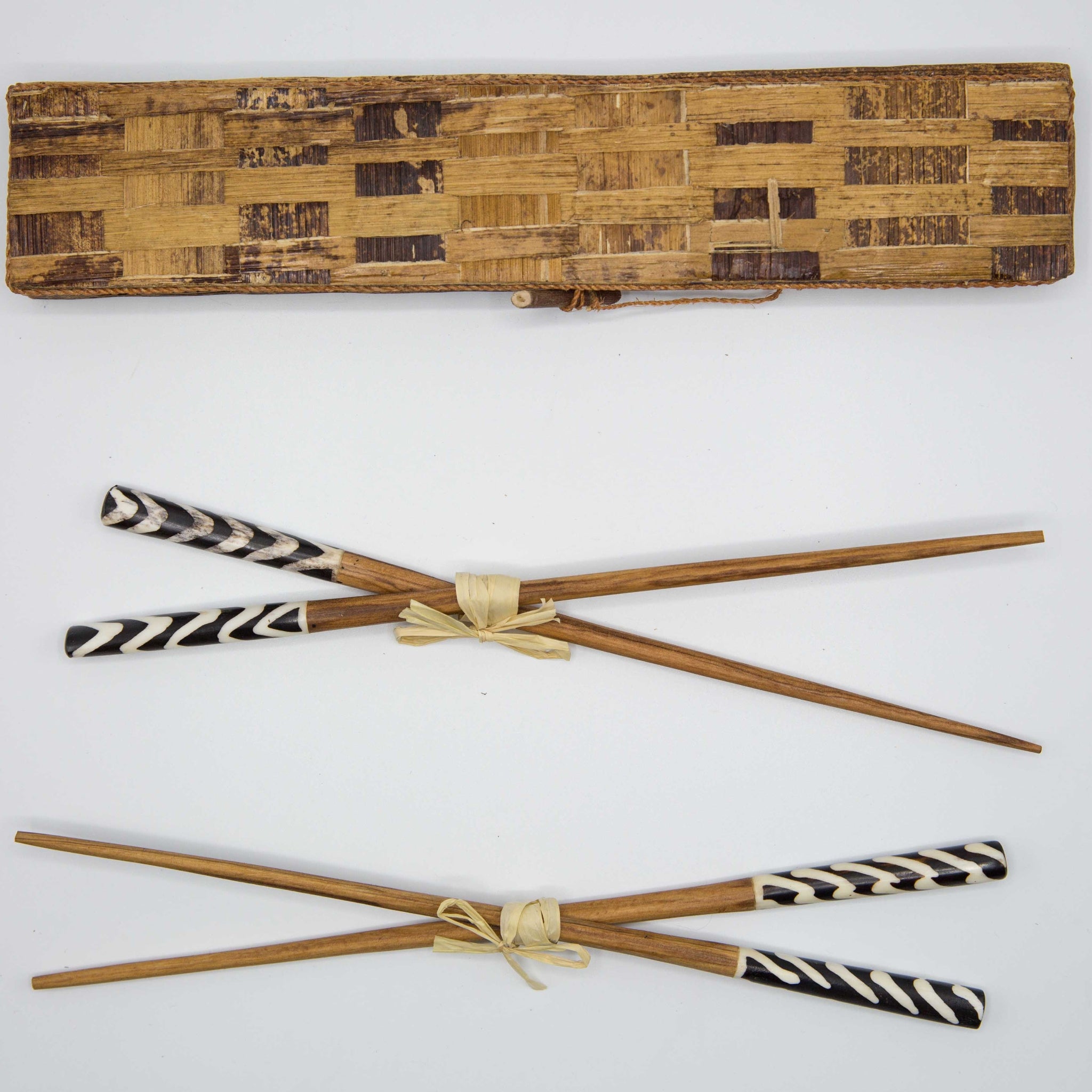 Four wooden chopsticks with black and white striped handles, tied in pairs with beige string, displayed below a matching woven bamboo case on a white background.