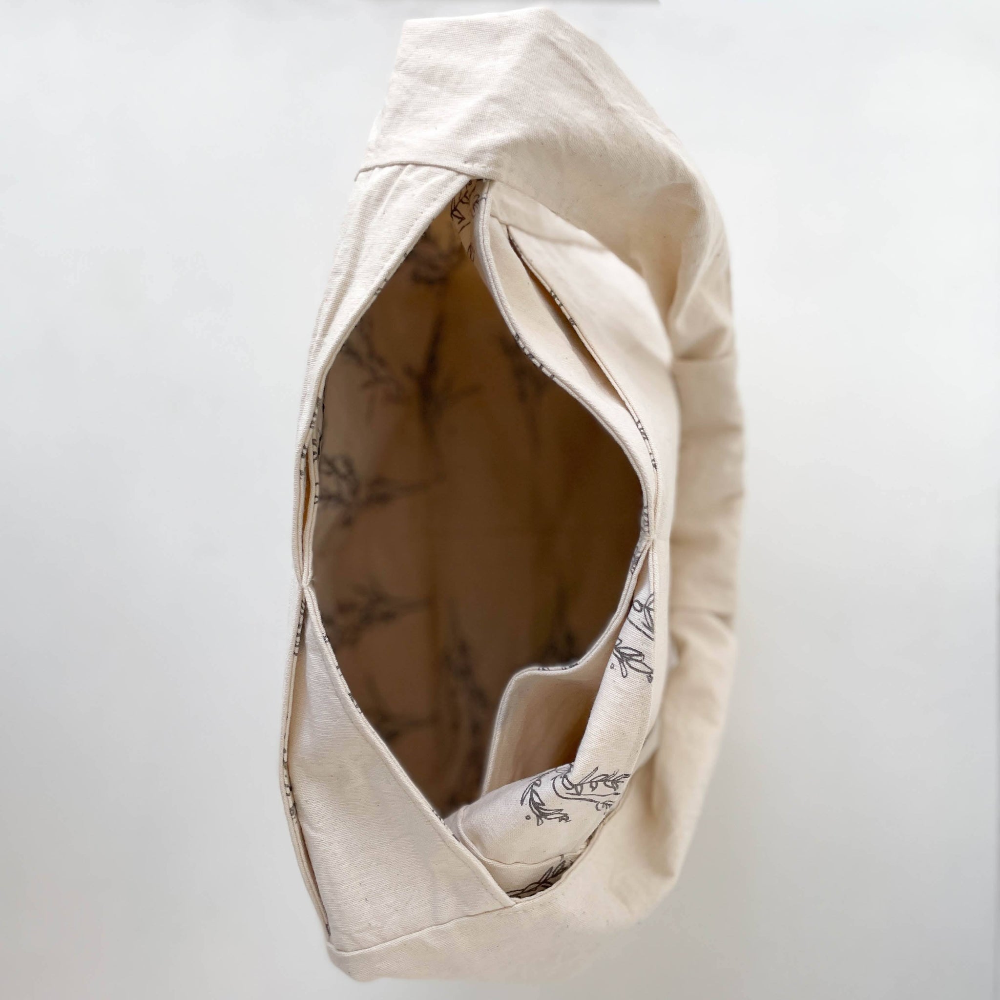 Beige fabric hobo bag with a patterned interior on a white background