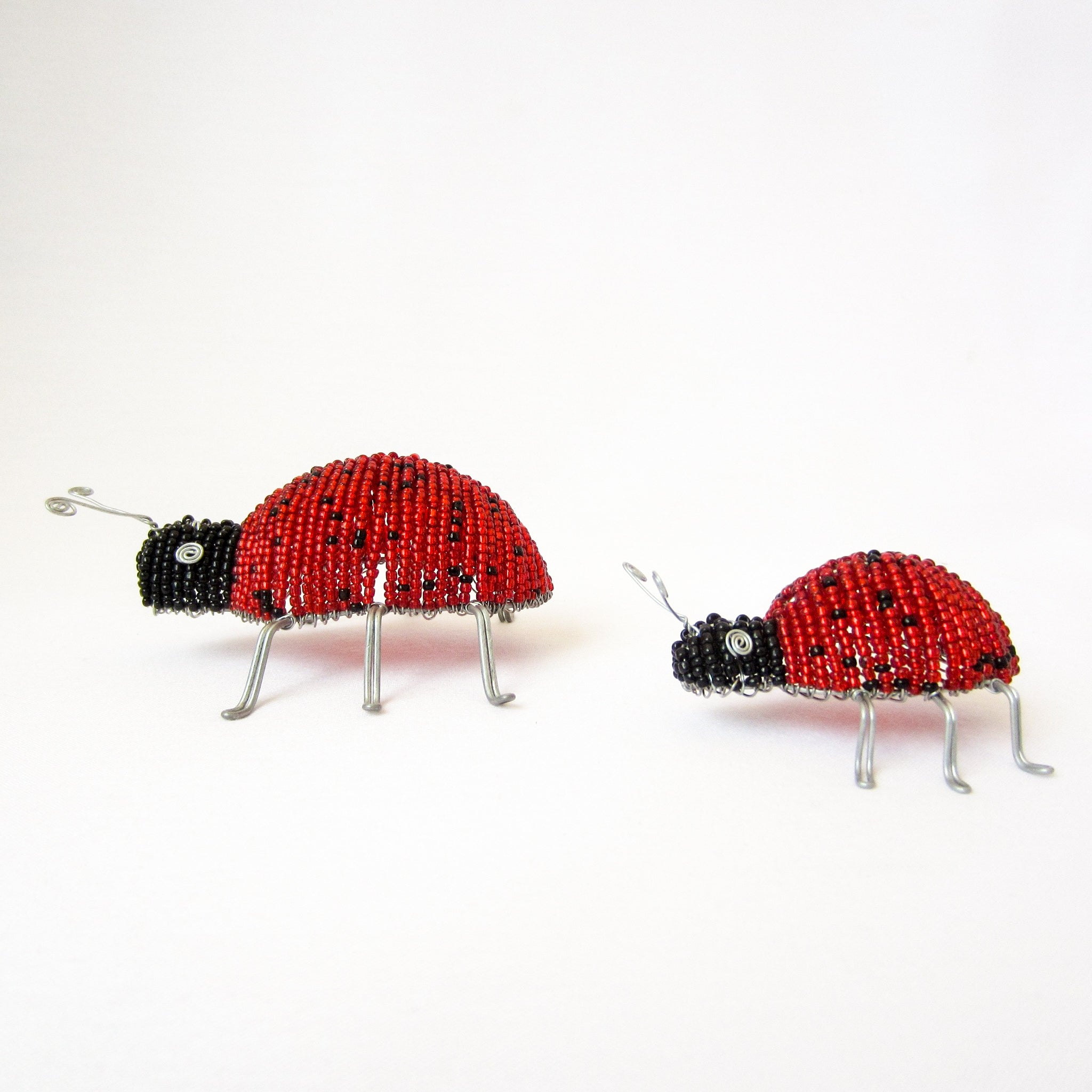 Two beaded ladybug ornaments on a white background