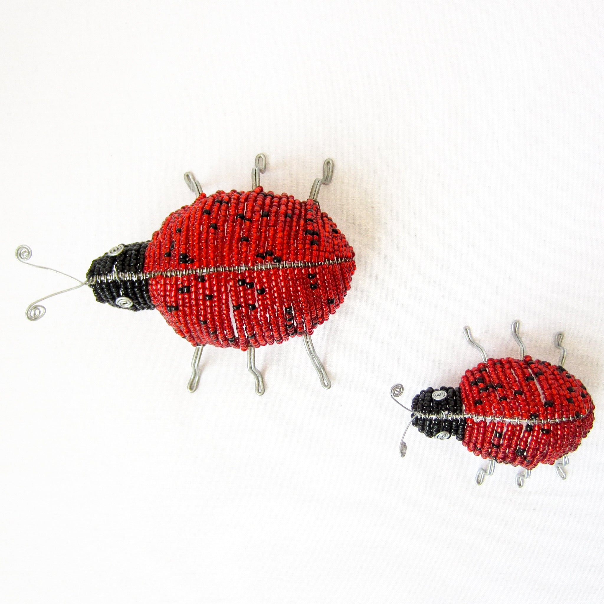 Two beaded ladybug ornaments on a white background