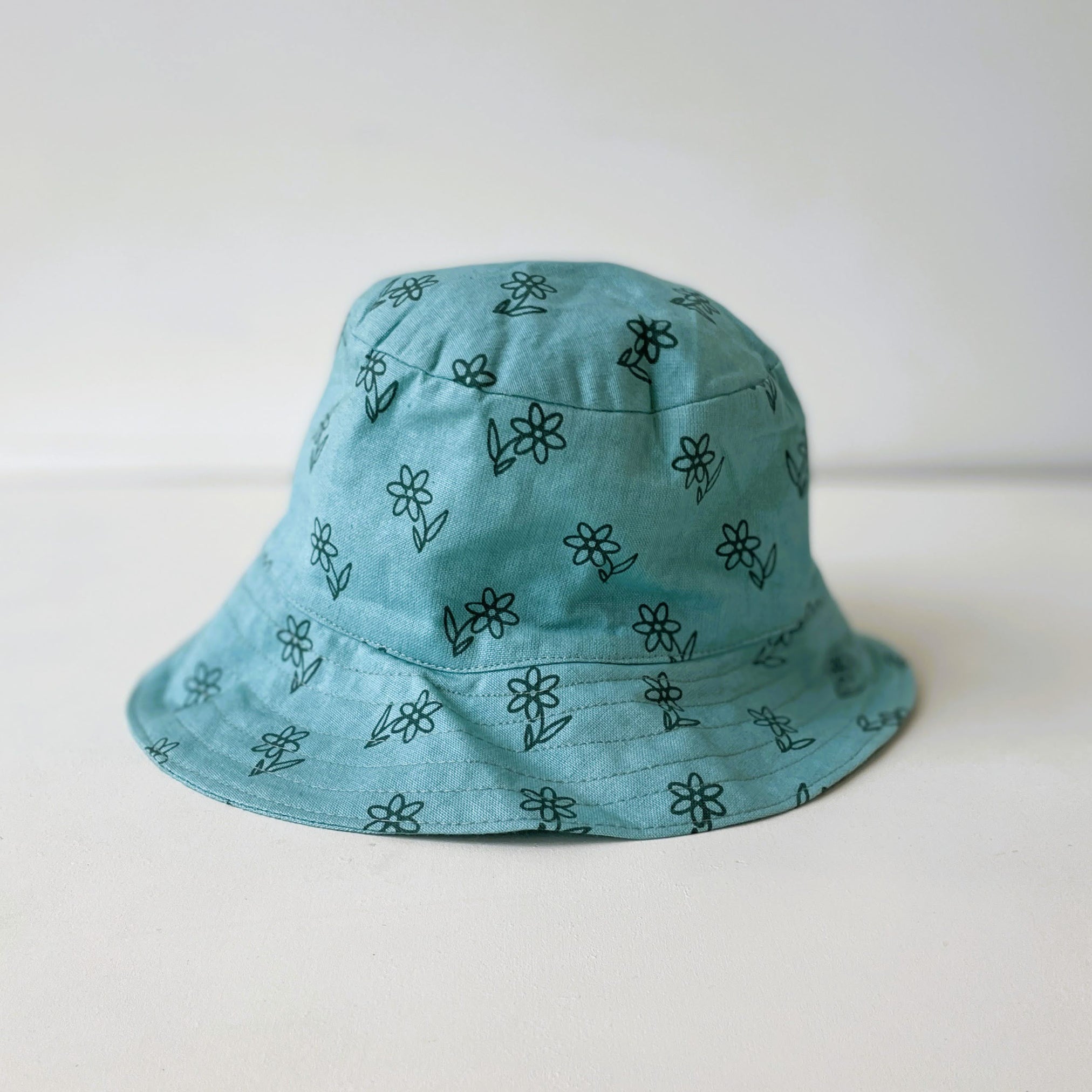 Blue bucket hat with black floral patterns on a white background
