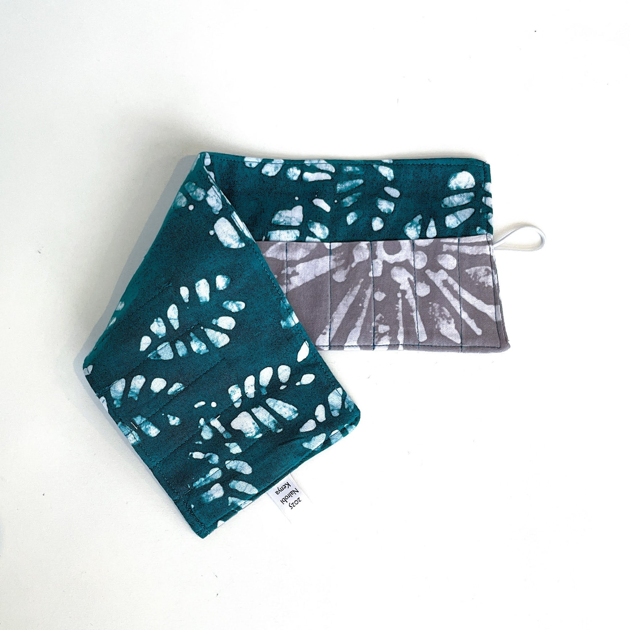 Two fabric pouches with teal and white pattern on a white background
