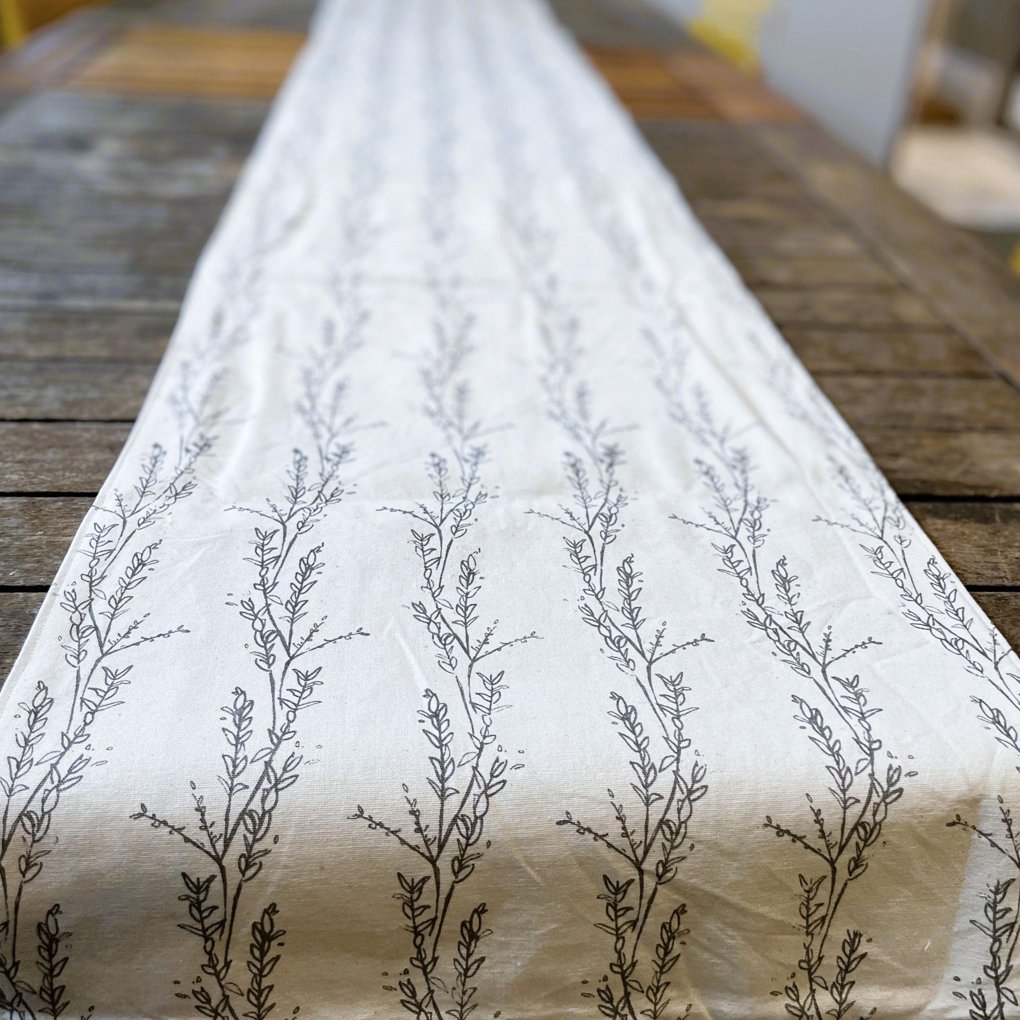 White fabric with black floral patterns on a wooden surface
