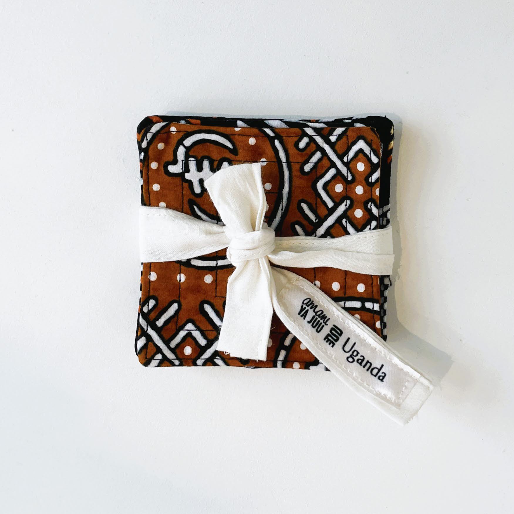 Brown fabric coasters with white pattern and a white ribbon, on a white background