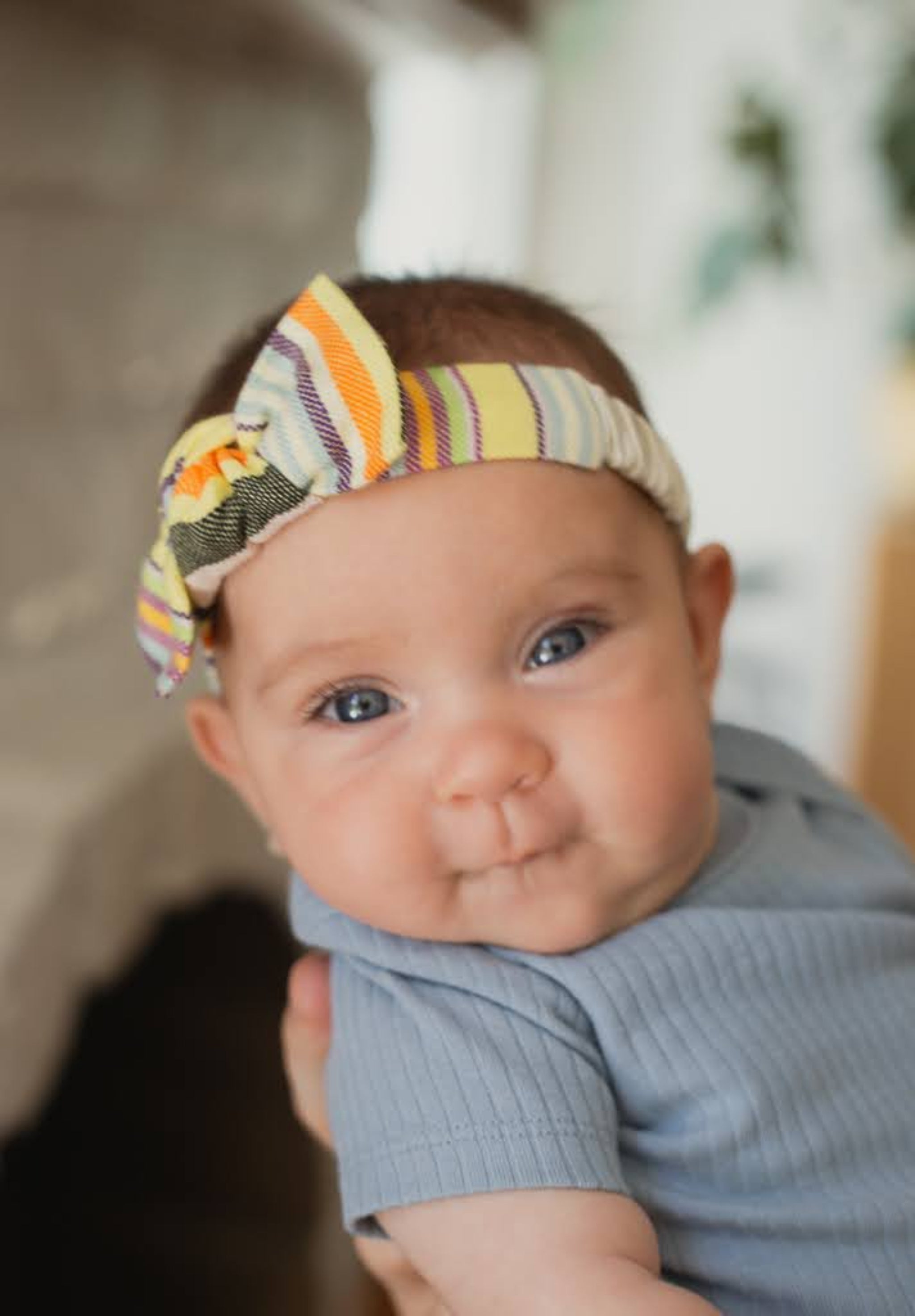 Baby wearing a colorful headband with a blurred background
