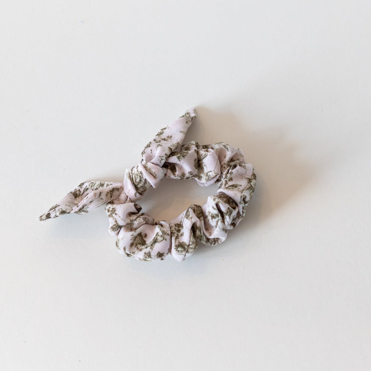Pale pink scrunchie with fern pattern on a white background.