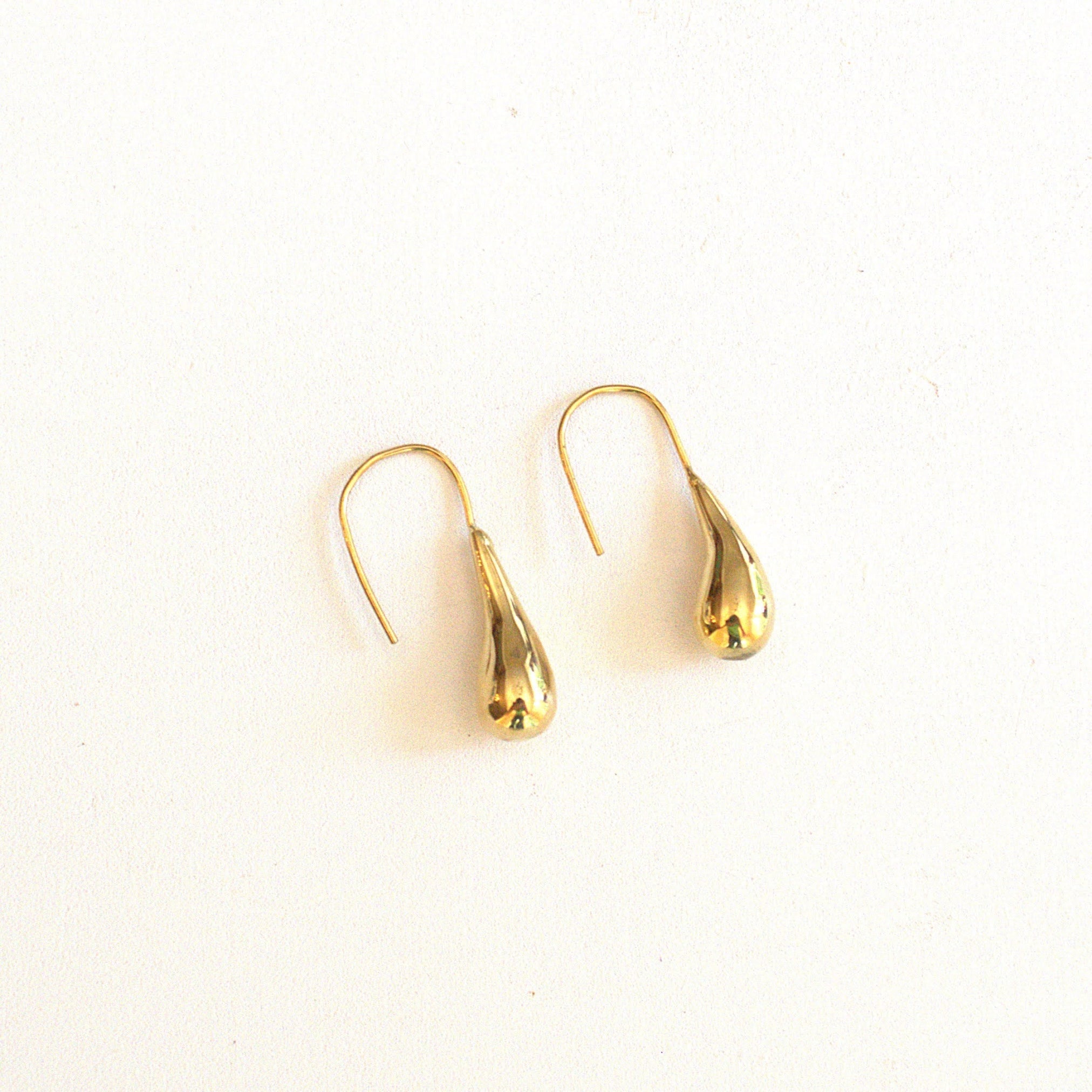 Brass raindrop shaped earrings on a white background