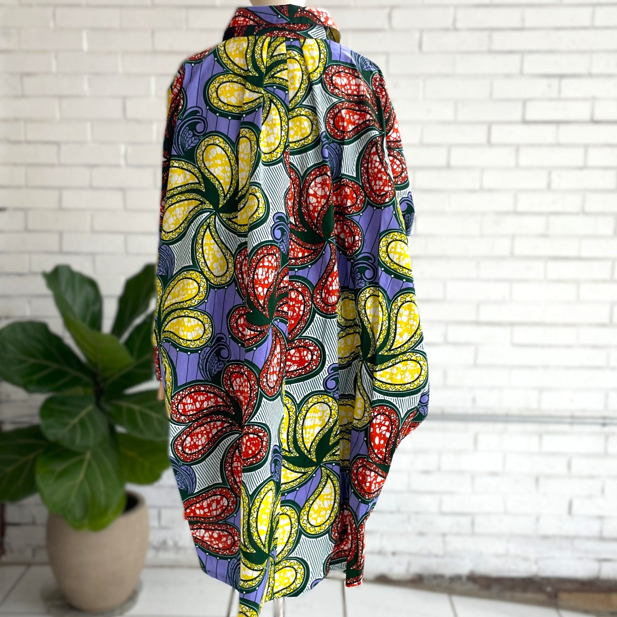 Colorful dress with floral pattern on a stand against a white brick wall.