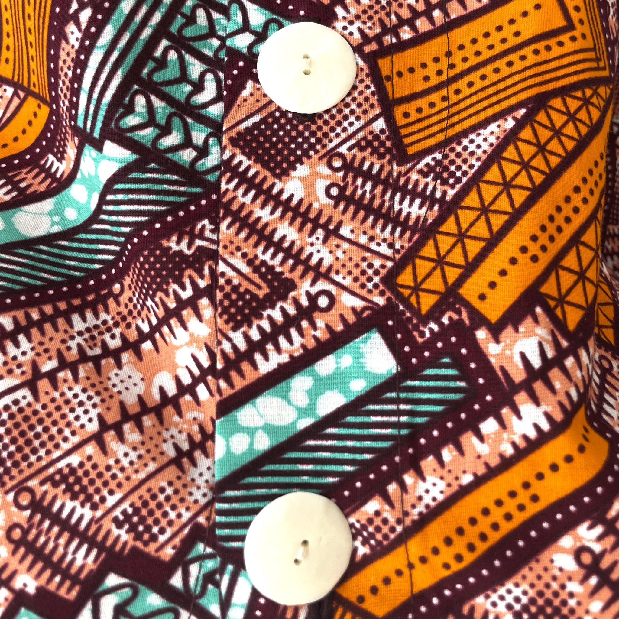 Close-up of a fabric with a colorful geometric pattern and two white buttons.