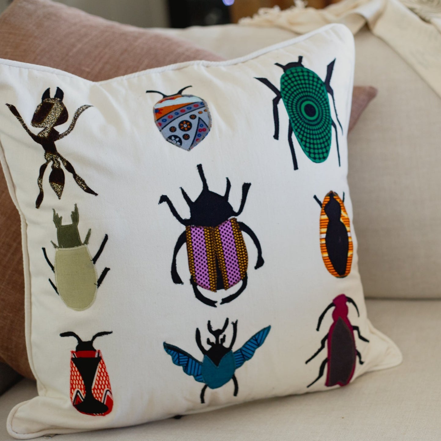 Decorative pillow with embroidered beetle designs on a couch.