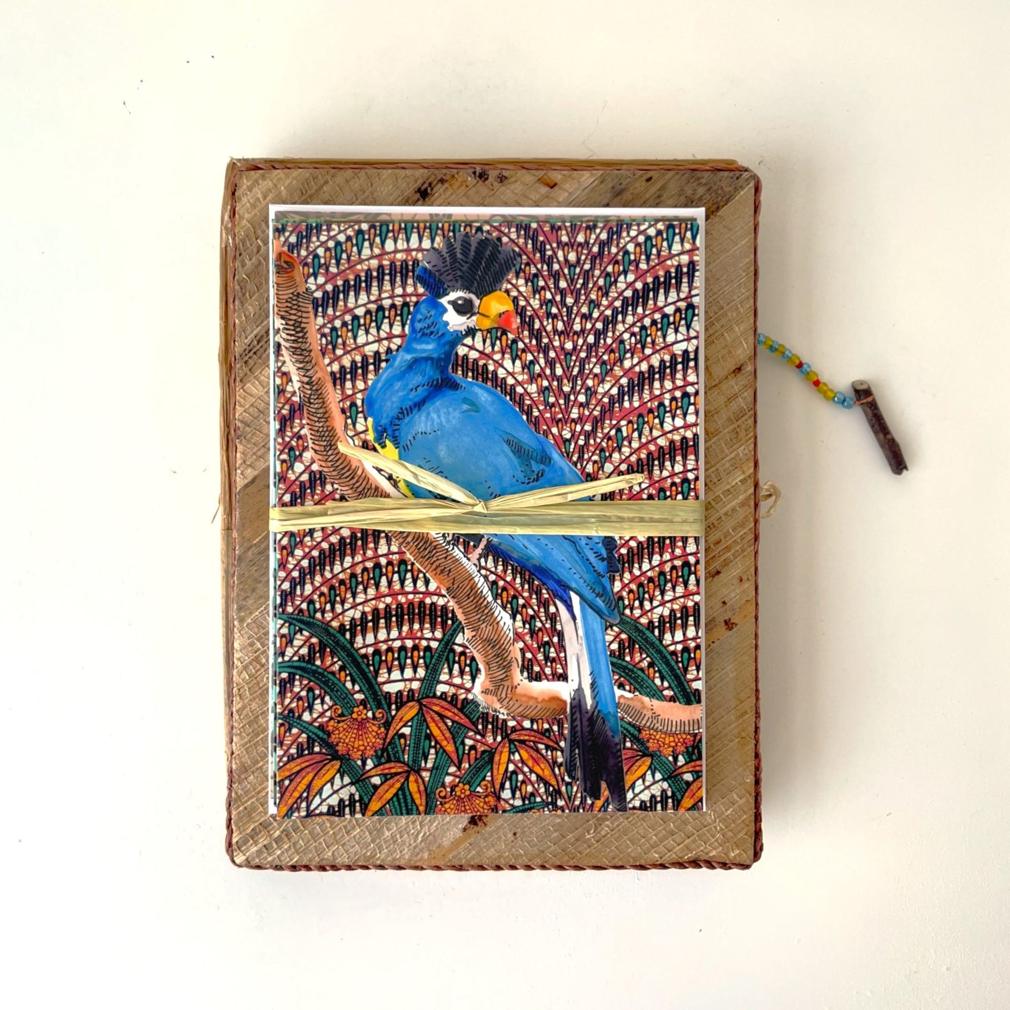 Card set with bird designs placed on top of a banana leaf box on a white background