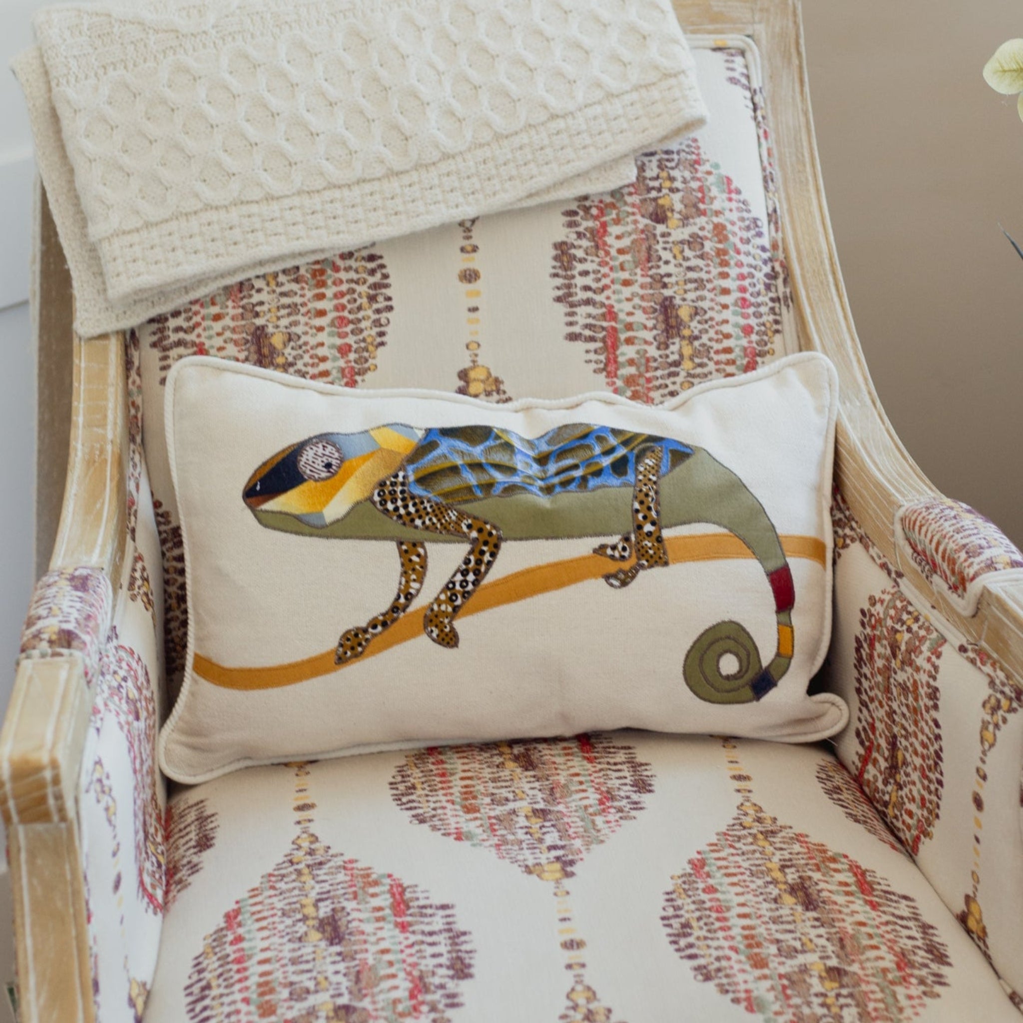 Decorative pillow with a chameleon design on a patterned chair
