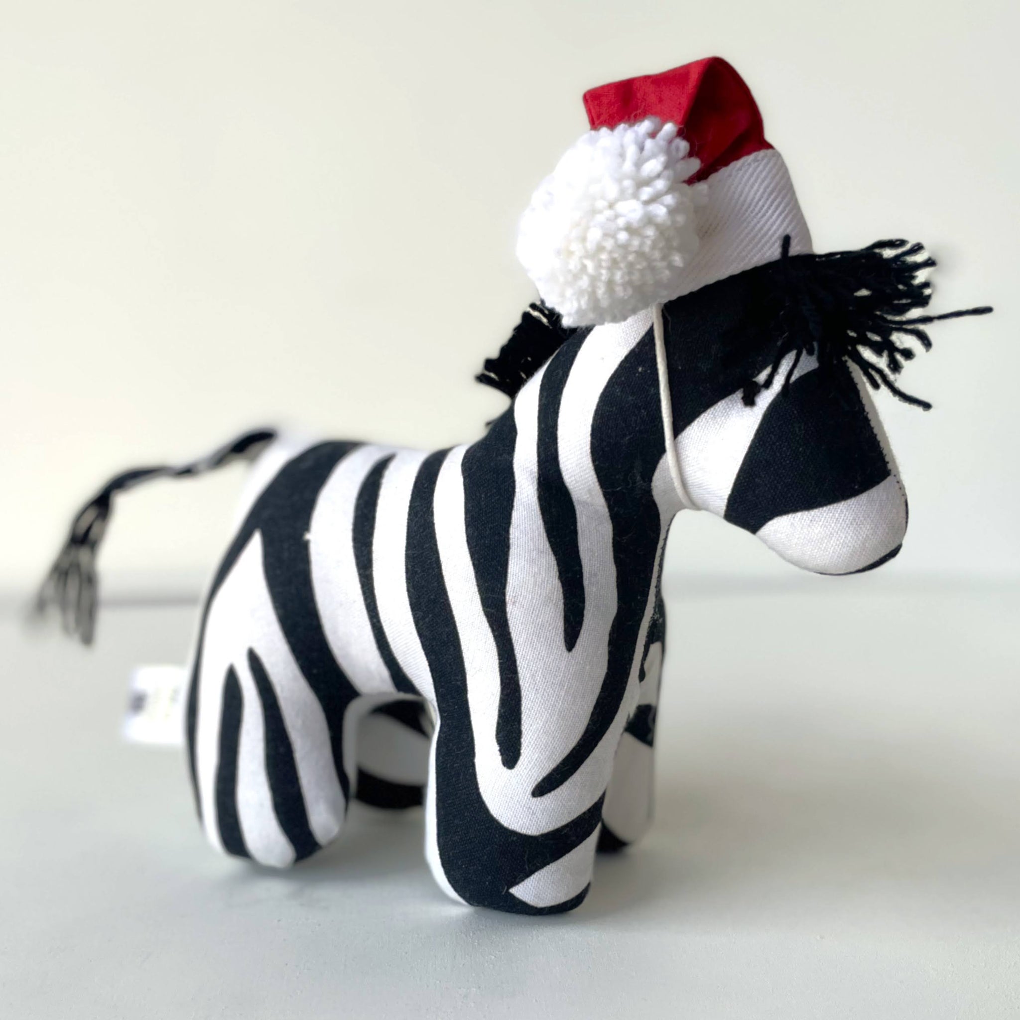Stuffed zebra toy wearing a Santa hat on a white background
