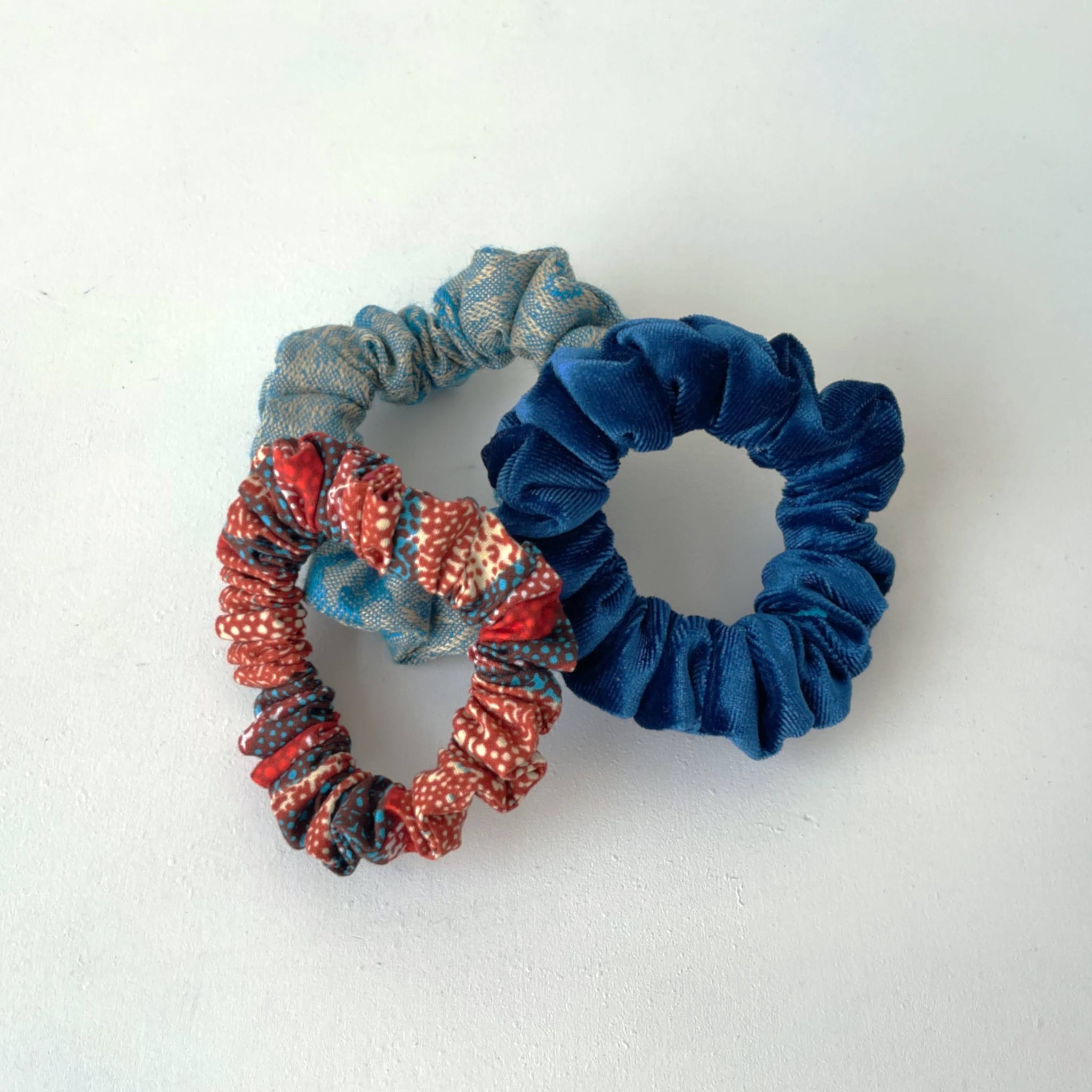 Set of three blue and orange scrunchies on a white background