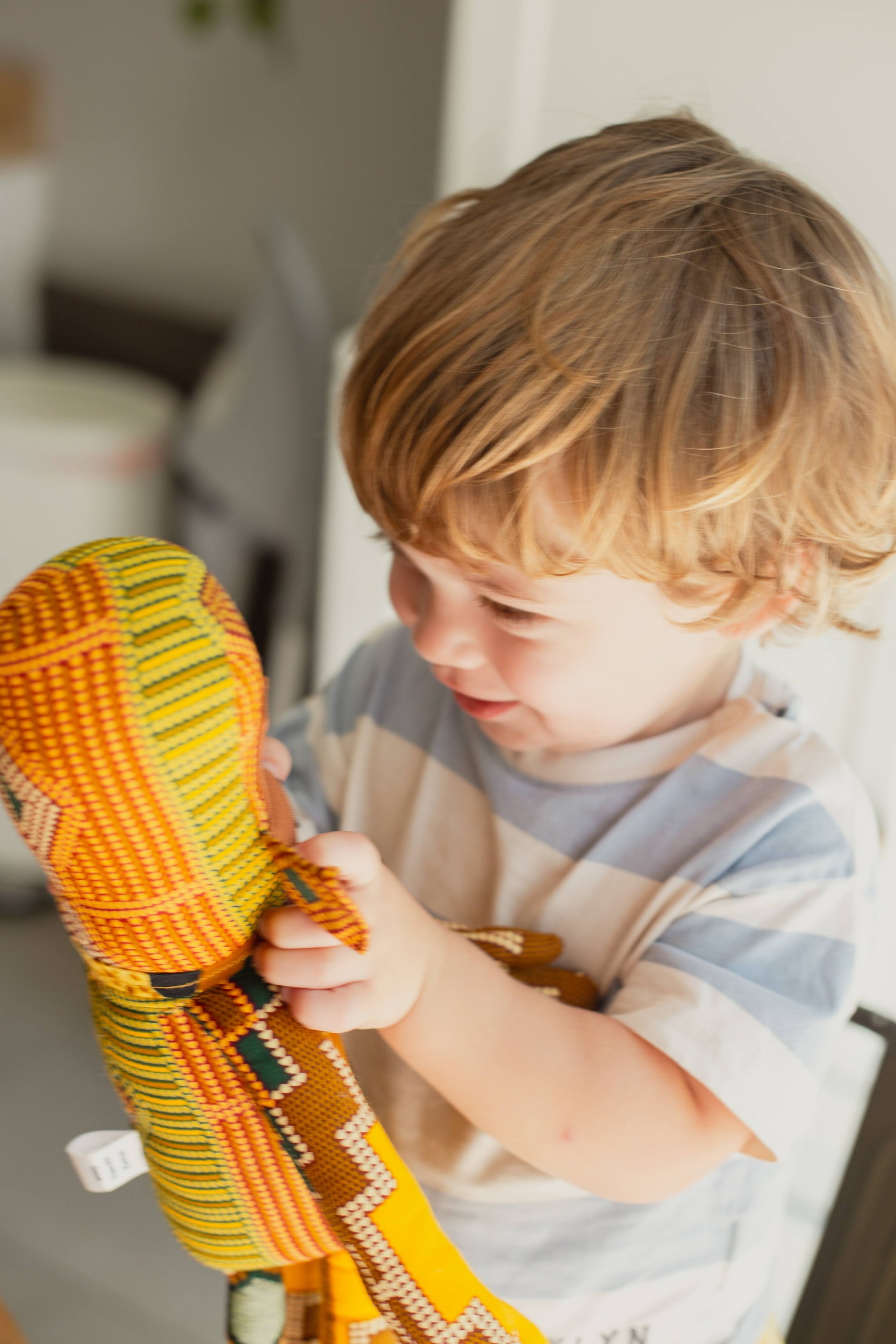 Child holding a colorful stuffed monkey indoors