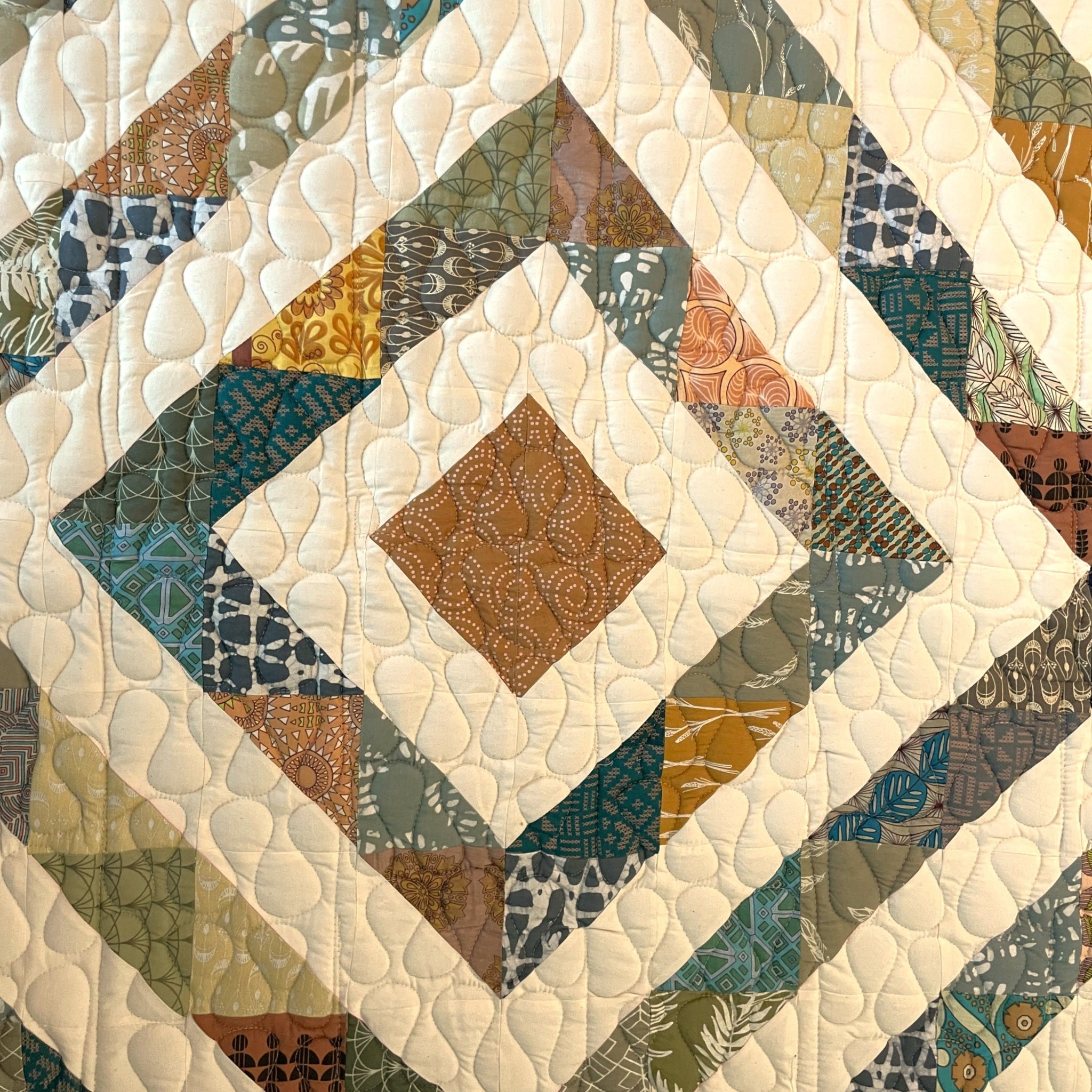 Quilt detail with geometric pattern featuring various colors and textures