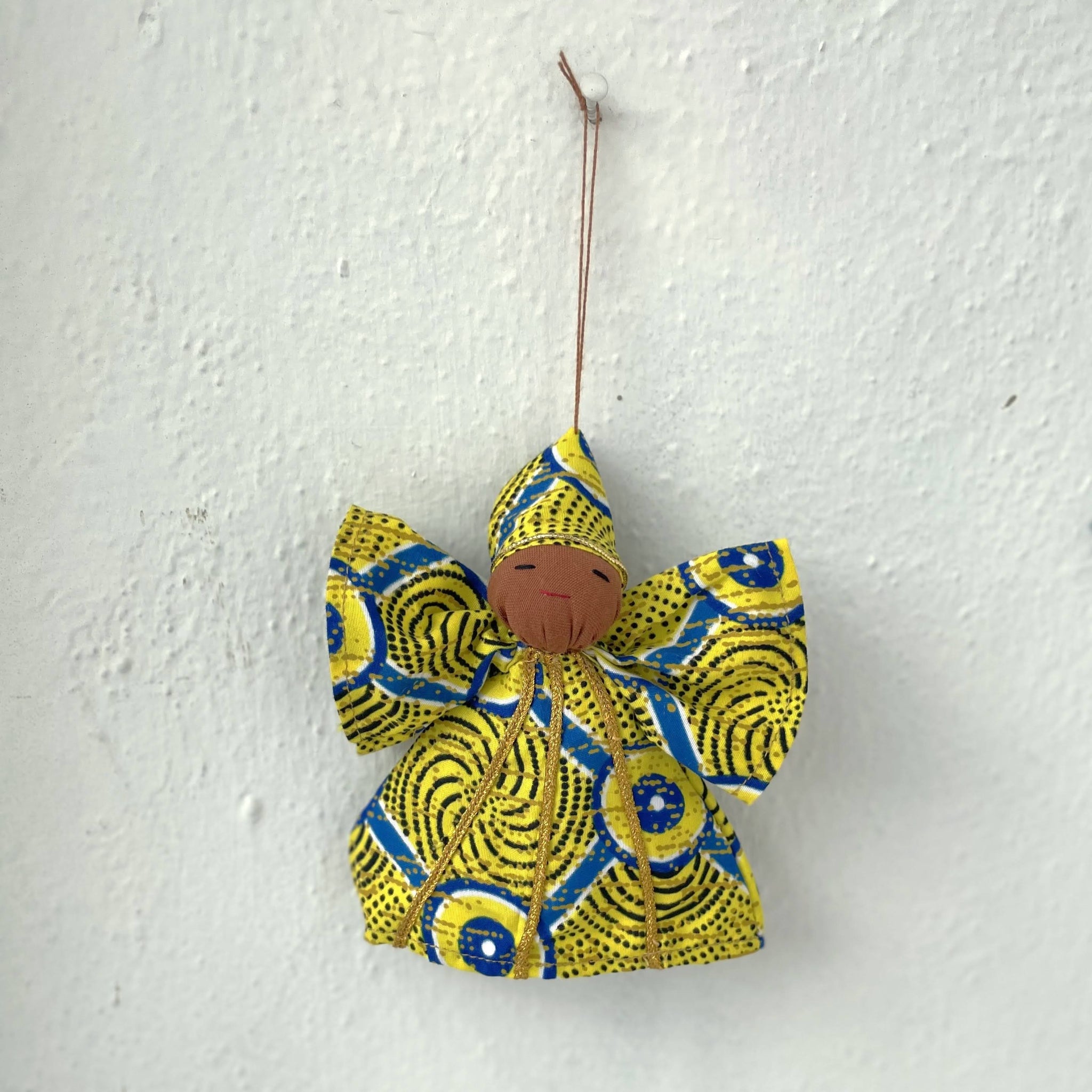 Angel-shaped ornament with yellow and blue pattern on a white wall