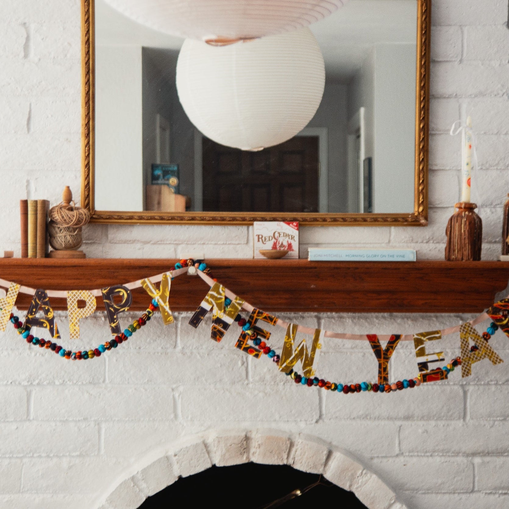 Decorative New Year's banner on a fireplace mantel with a mirror above.