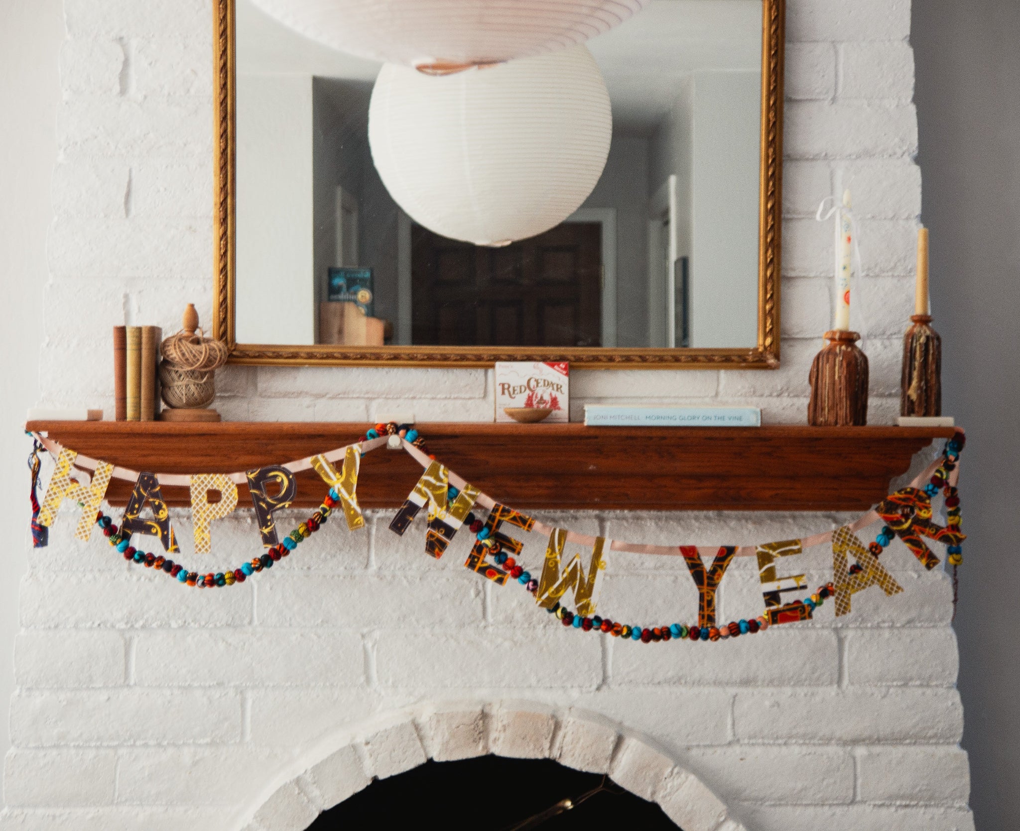 Decorative New Year's banner on a fireplace mantel with a mirror above.