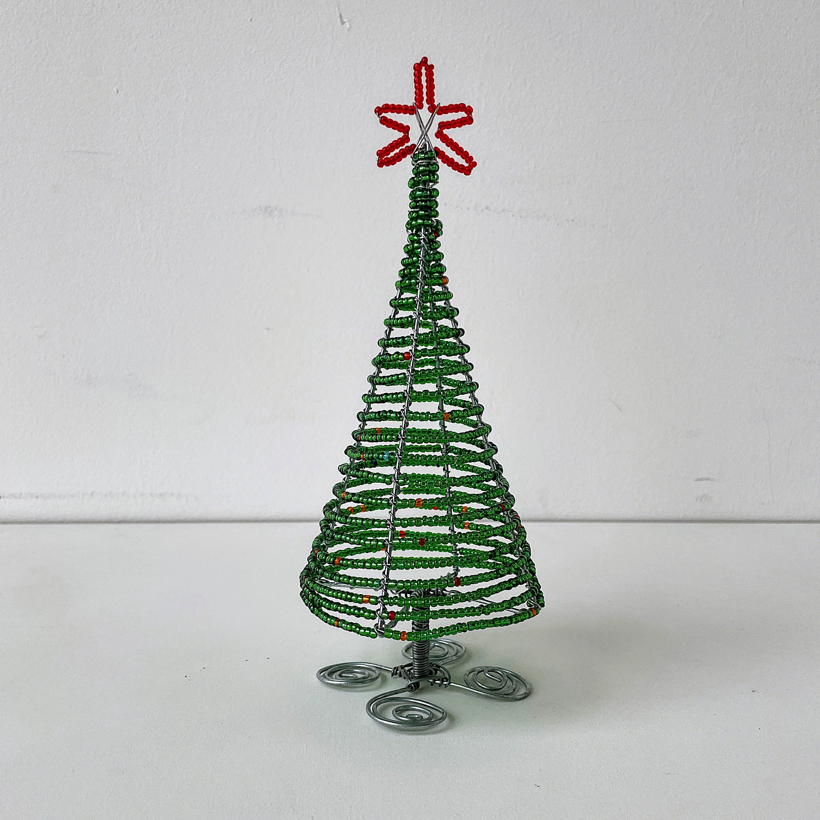 Decorative beaded Christmas tree with a red star on top against a white background