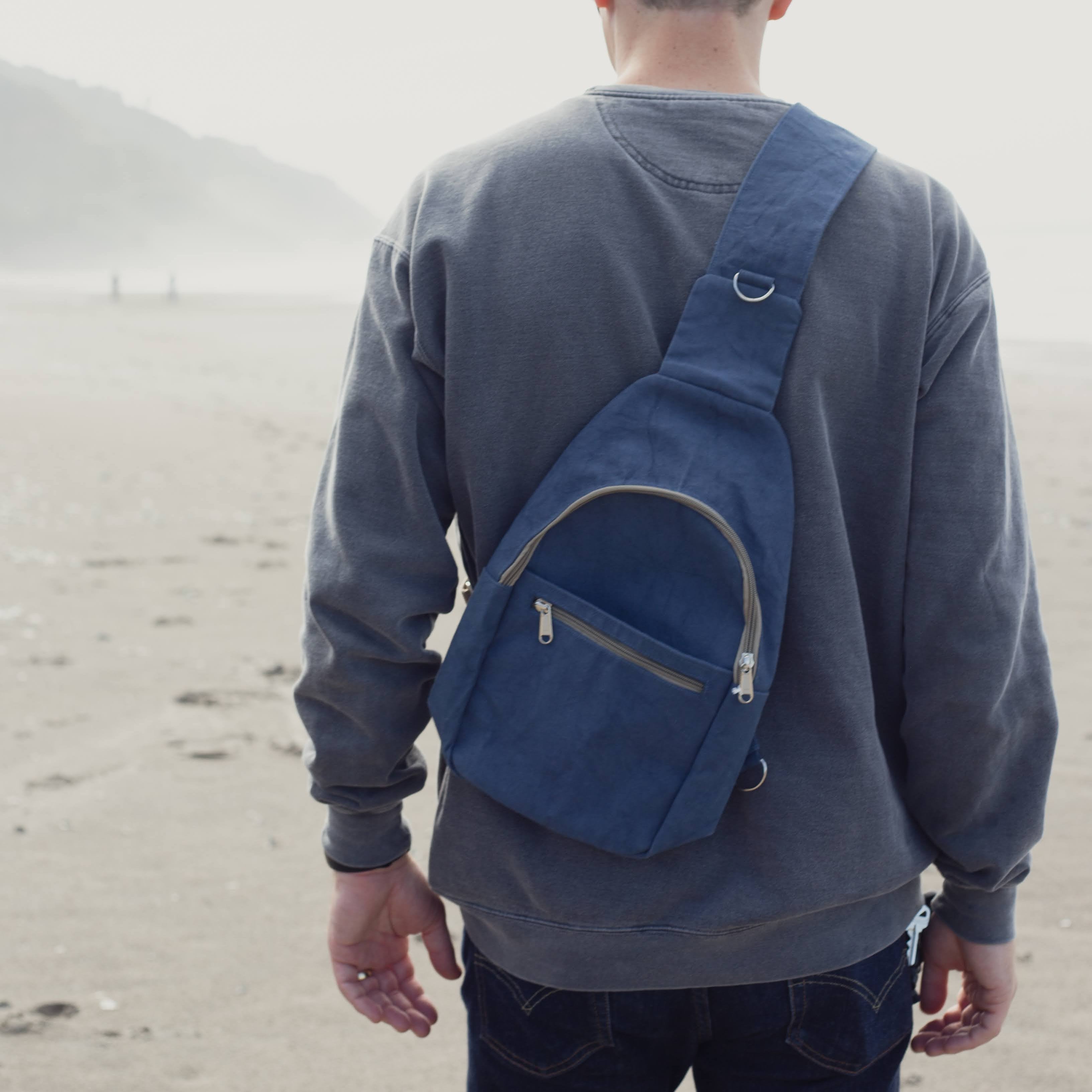 Man wearing a blue backpack on a beach