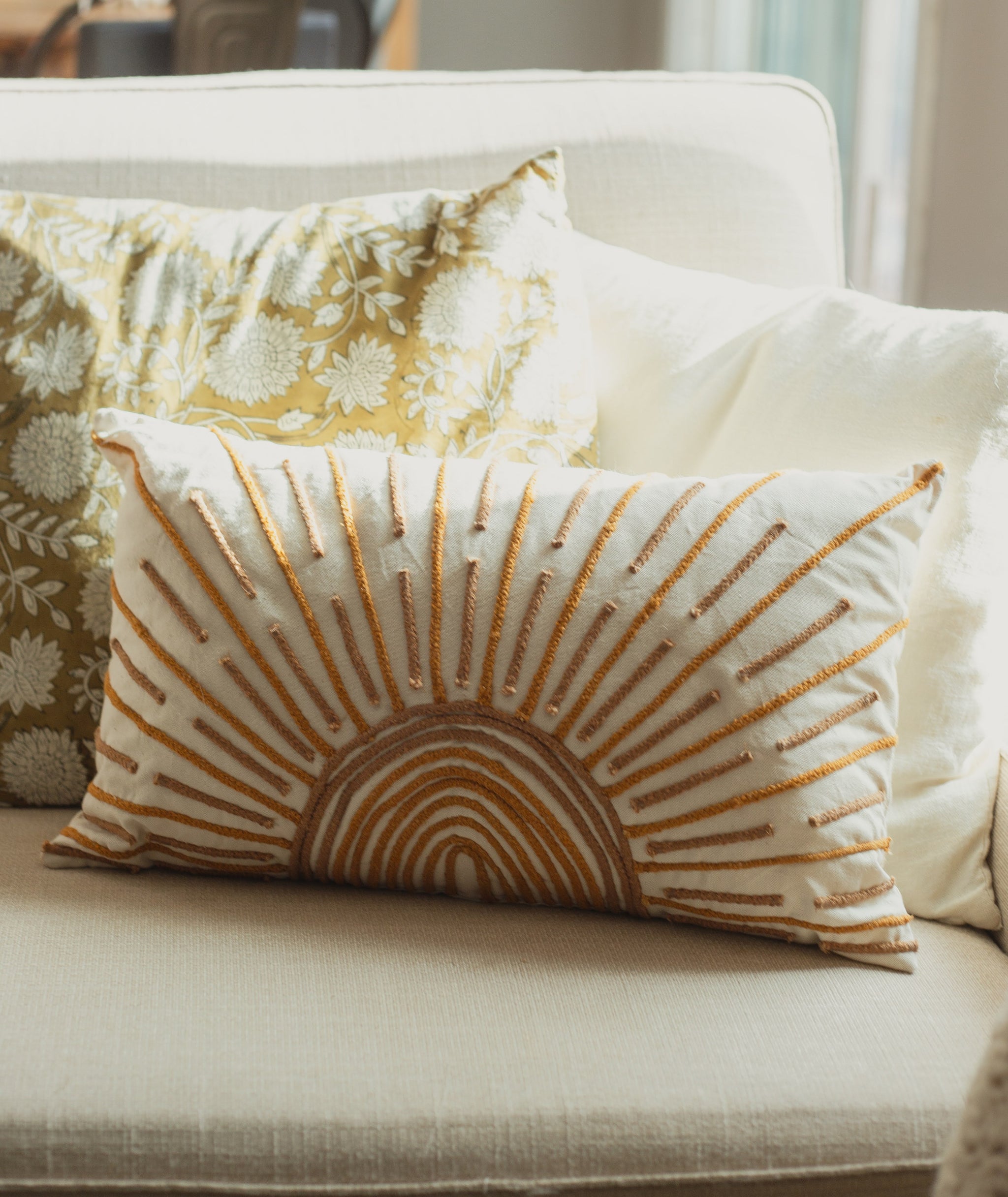 Decorative pillows on a sofa with a sunburst pattern and floral design.