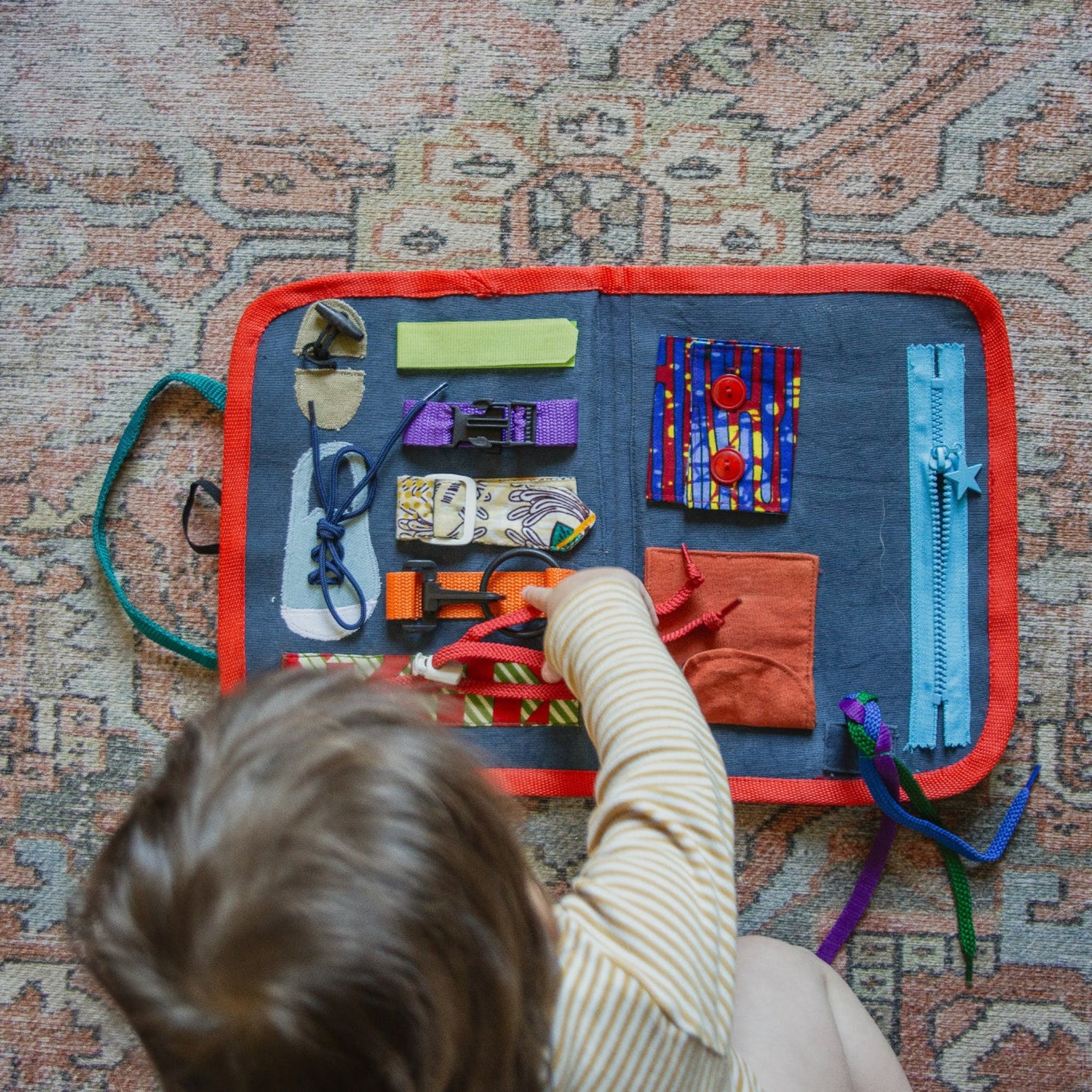 Child playing with a toy set on a colorful mat on a patterned rug.