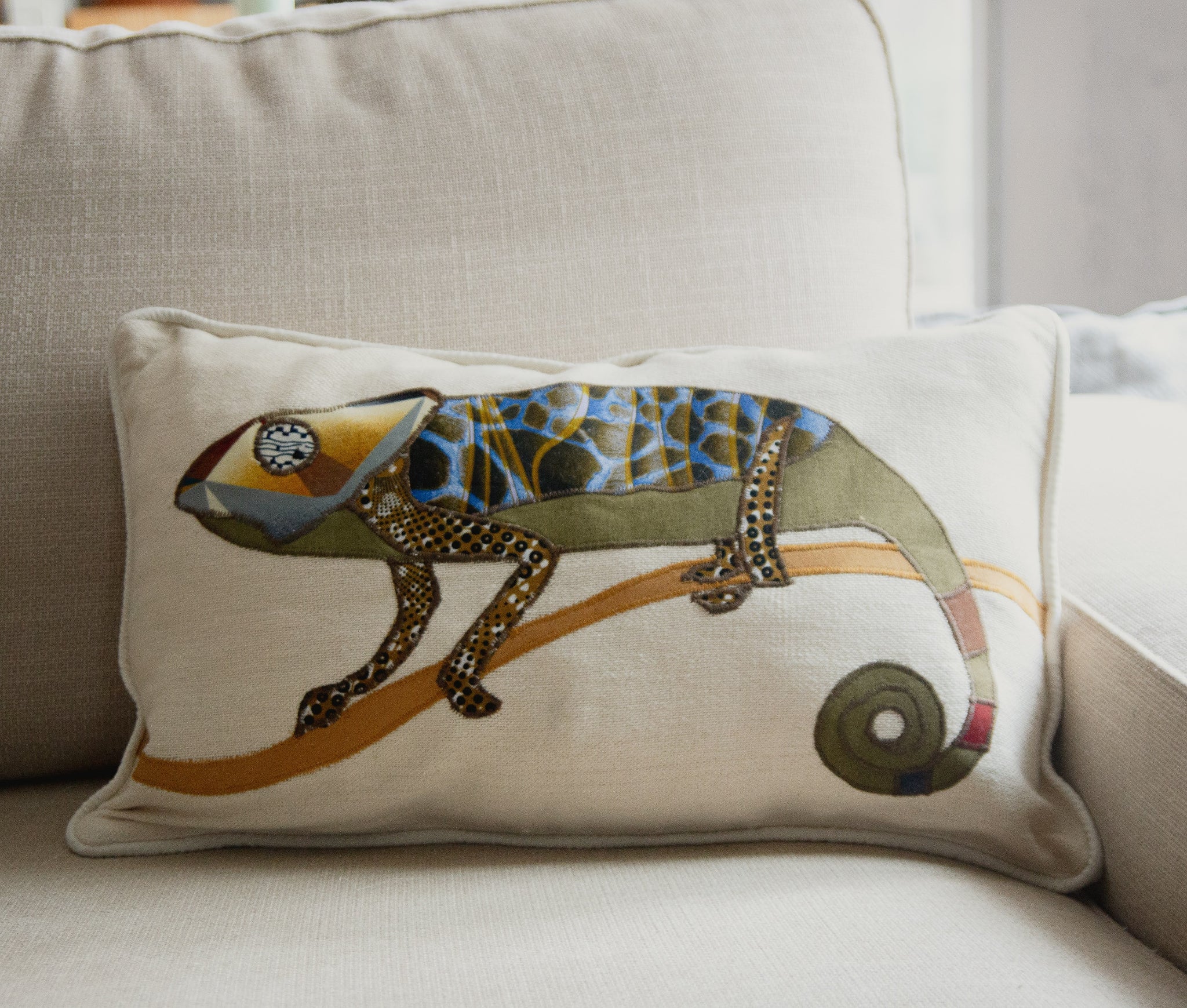 Decorative pillow with a chameleon design on a beige couch