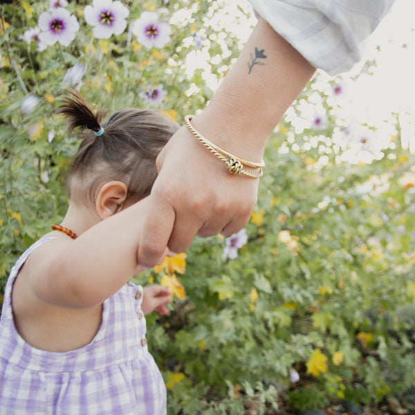 Child holding hands with an adult in a garden setting