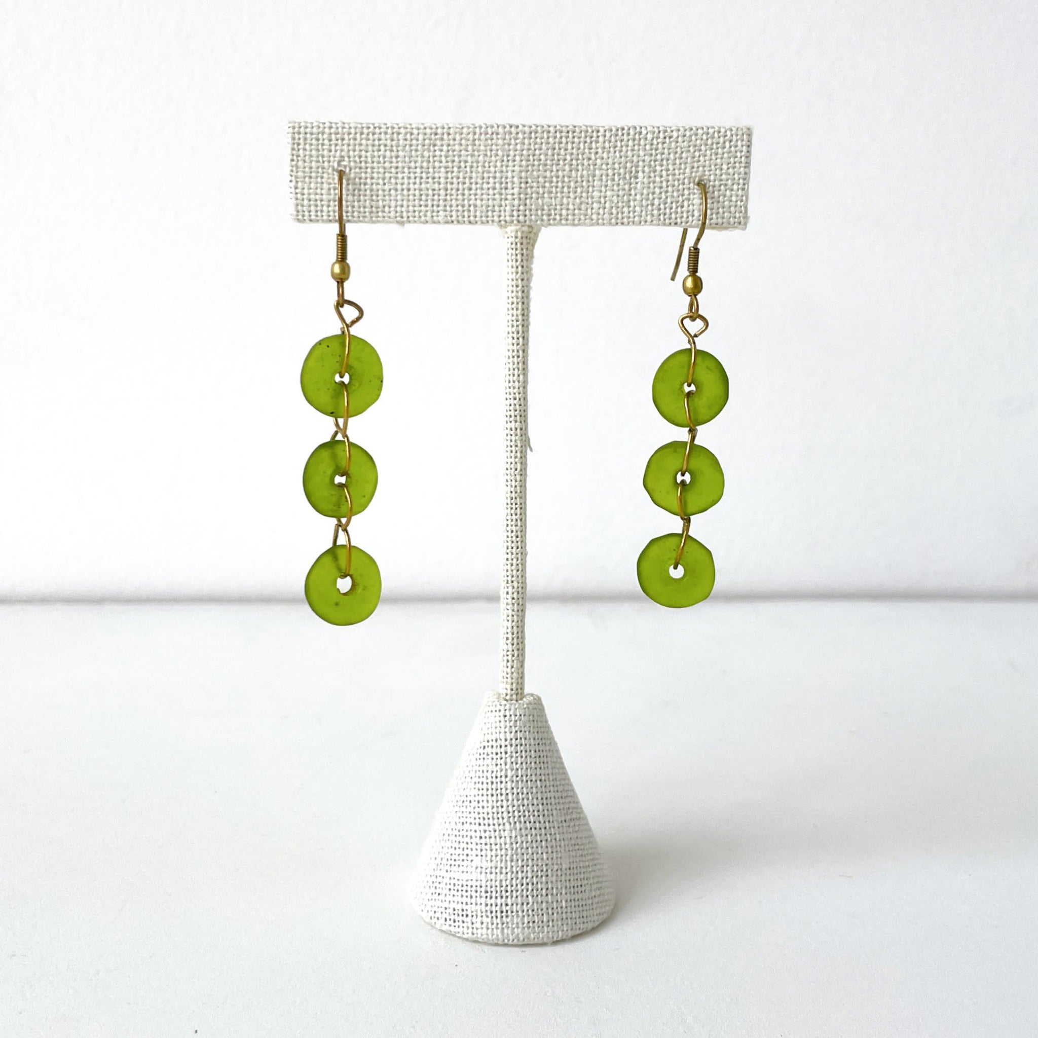 Green glass button earrings on a white background