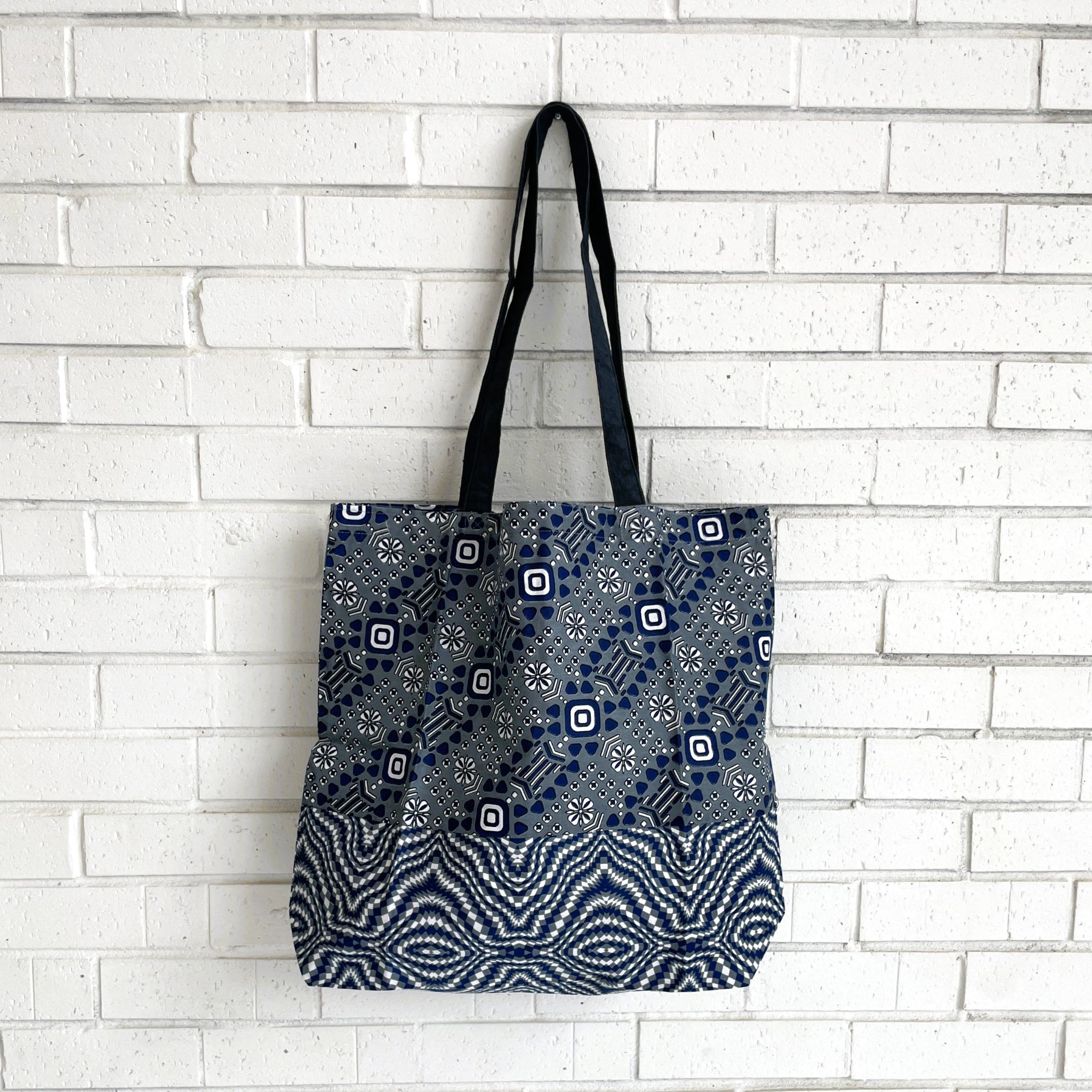 Tote bag with blue and white pattern against a white brick wall