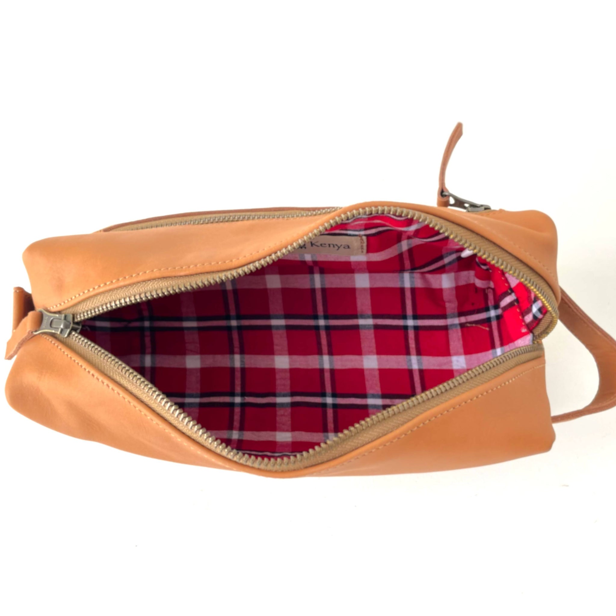 Tan leather bag with red plaid interior on a white background