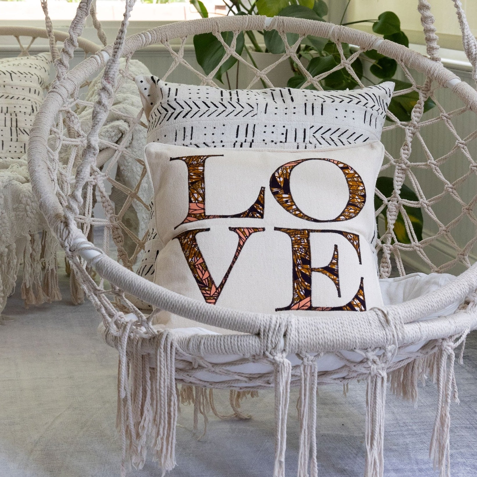 White macrame chair with a 'LOVE' pillow in a cozy indoor setting.