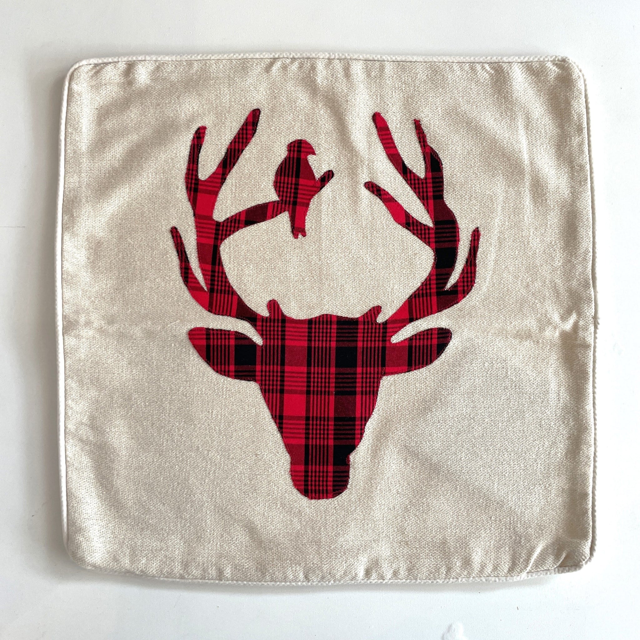 Fabric square pillowcase with a red plaid deer head design on a white background