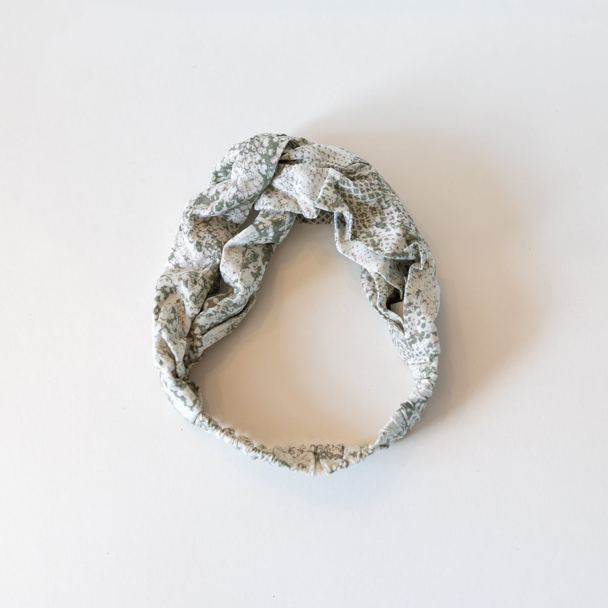 Sage green and white twisted headband on a white background.
