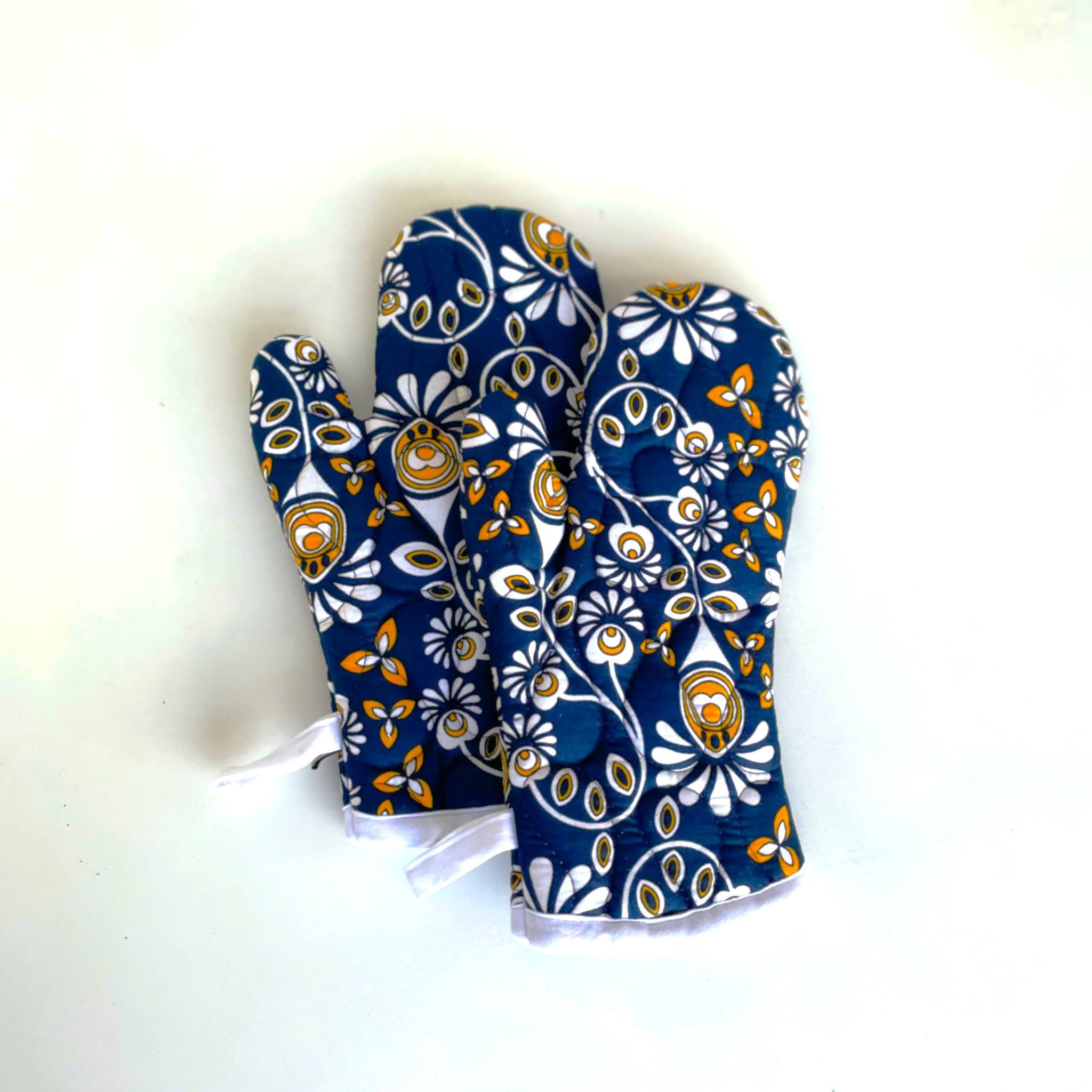 Navy, gold, and white floral oven mitts on a white background