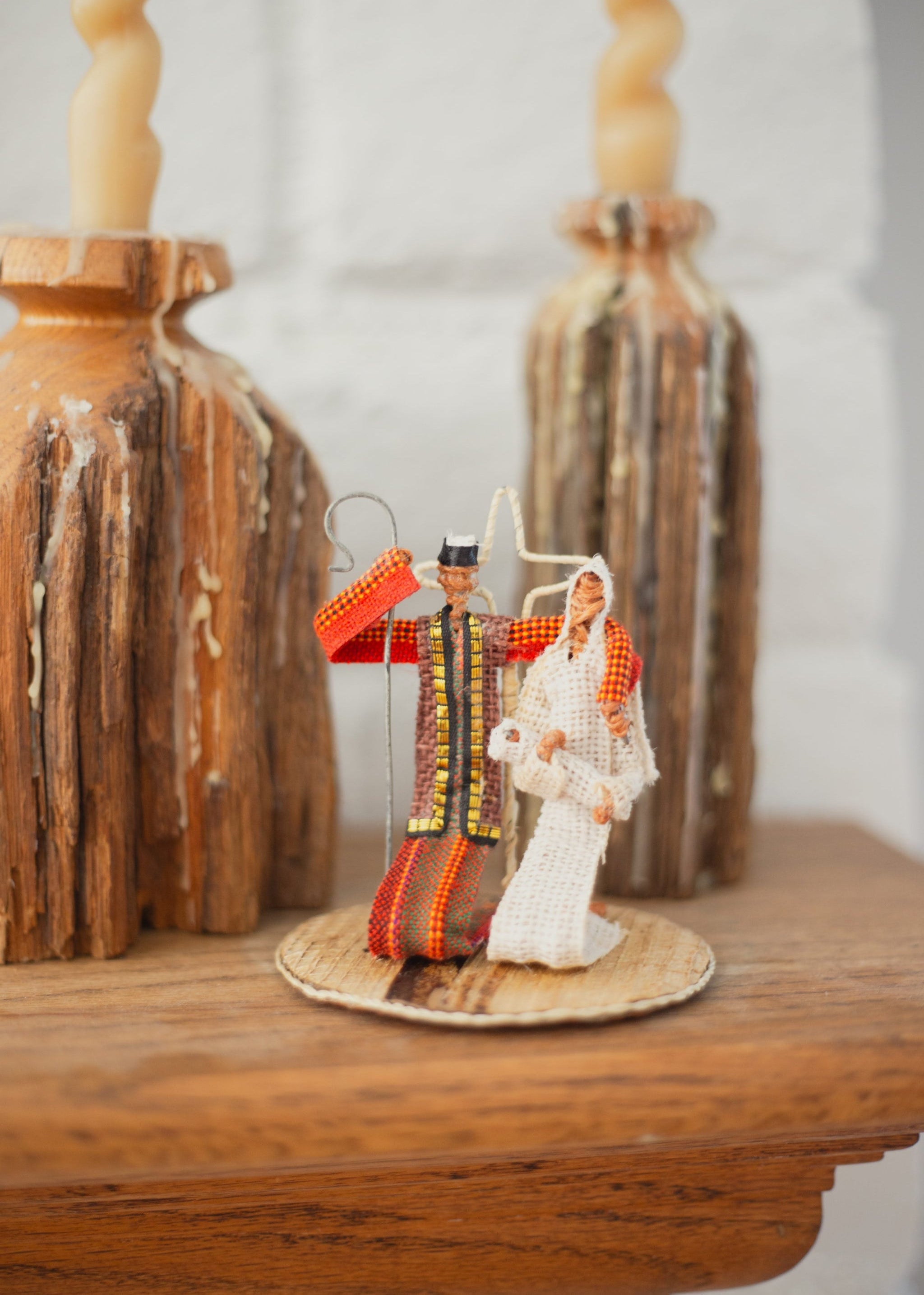 Simple nativity set with Mary, Joseph, and baby Jesus on a wooden surface with decorative elements.