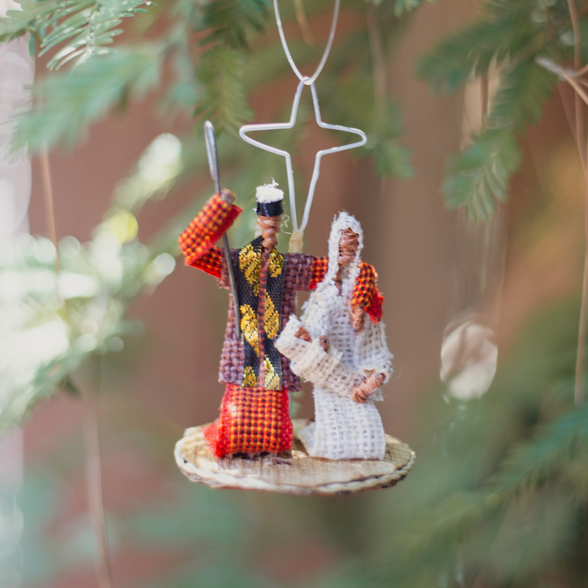 Nativity Christmas ornament with large star, hanging on a tree.