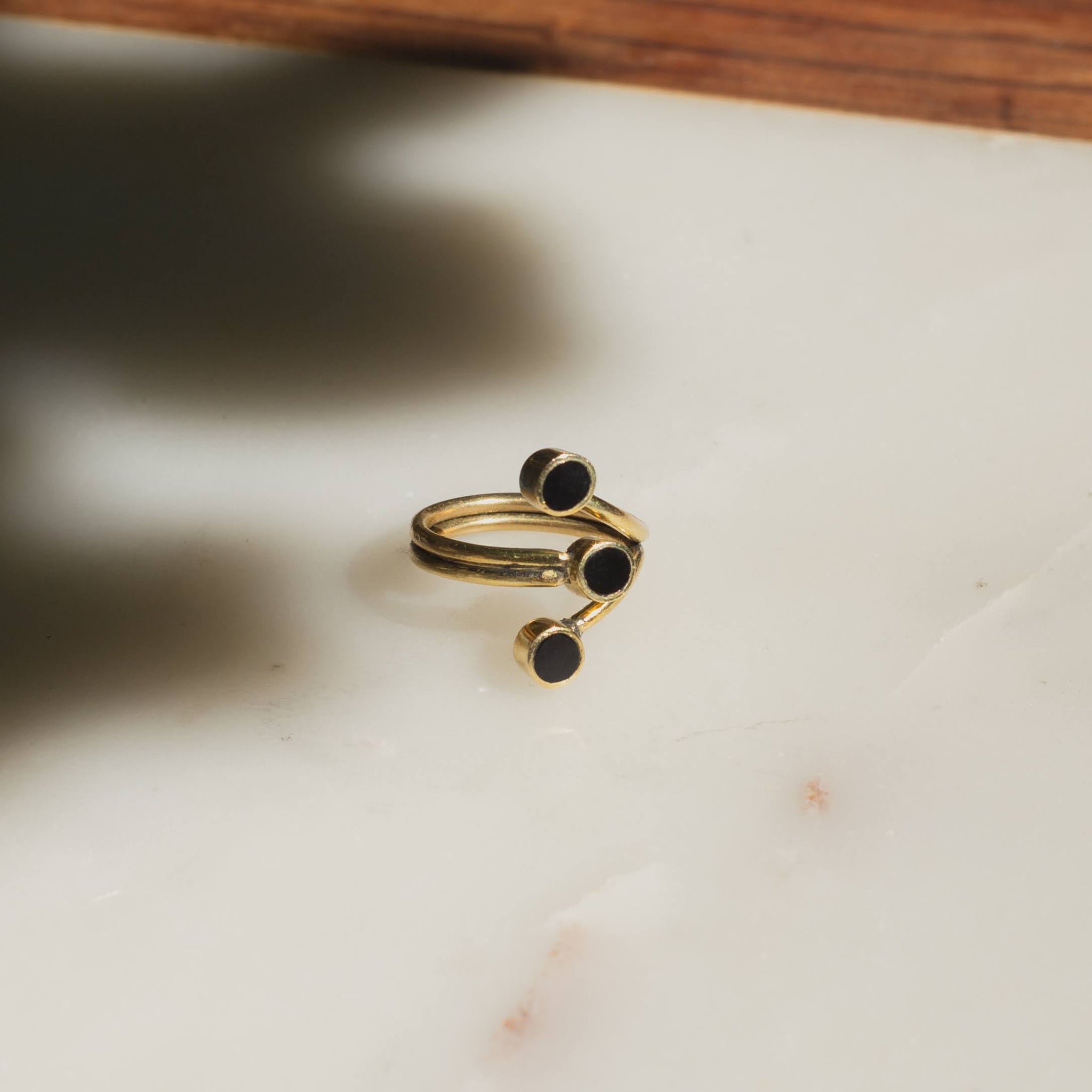 Brass and black horn discs ring on a marble surface
